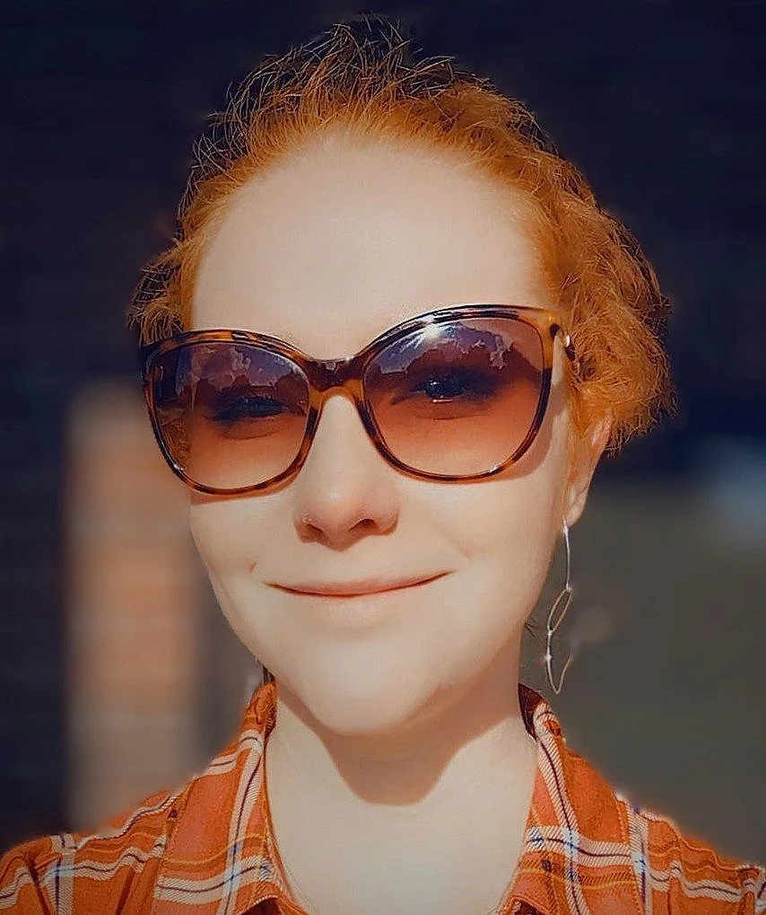 Heather Tuomisto, a smiling woman with red hair wearing sunglasses