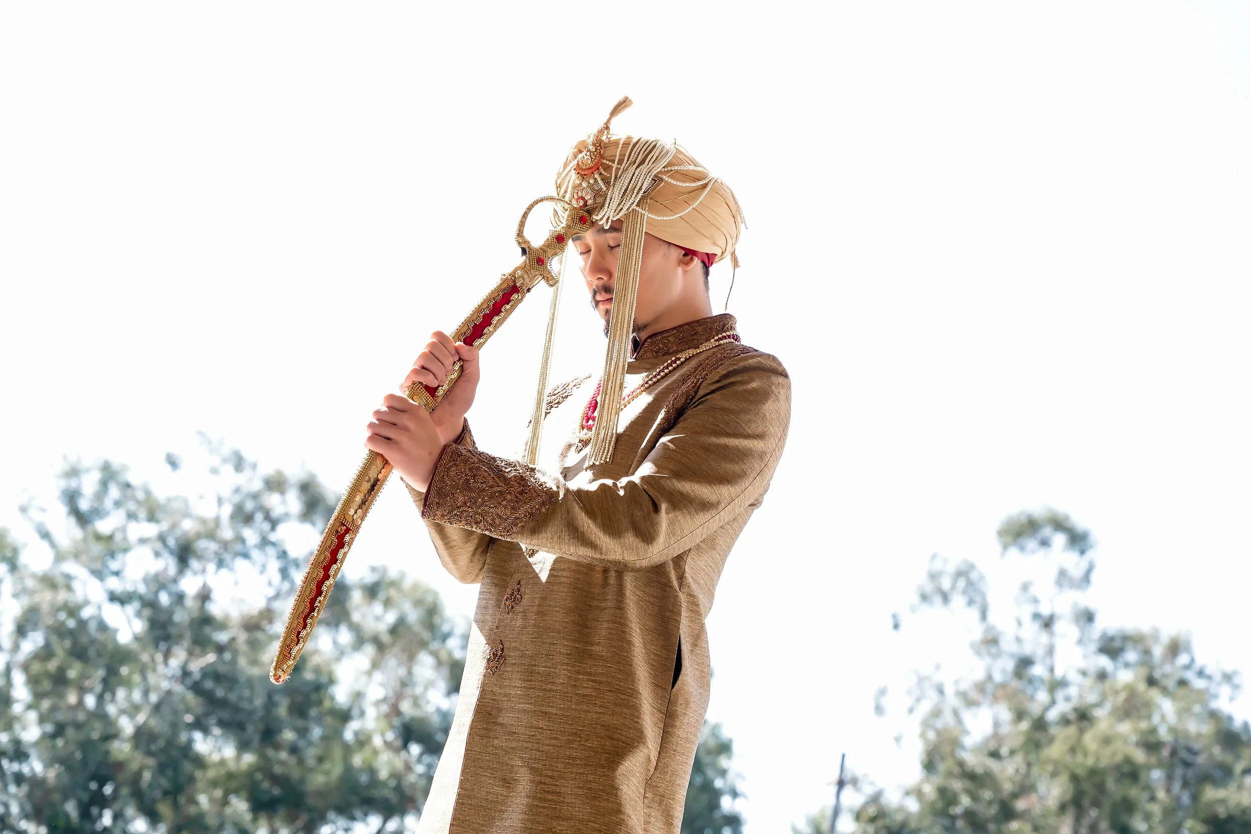 Man in traditional Indian attire holding a sword.