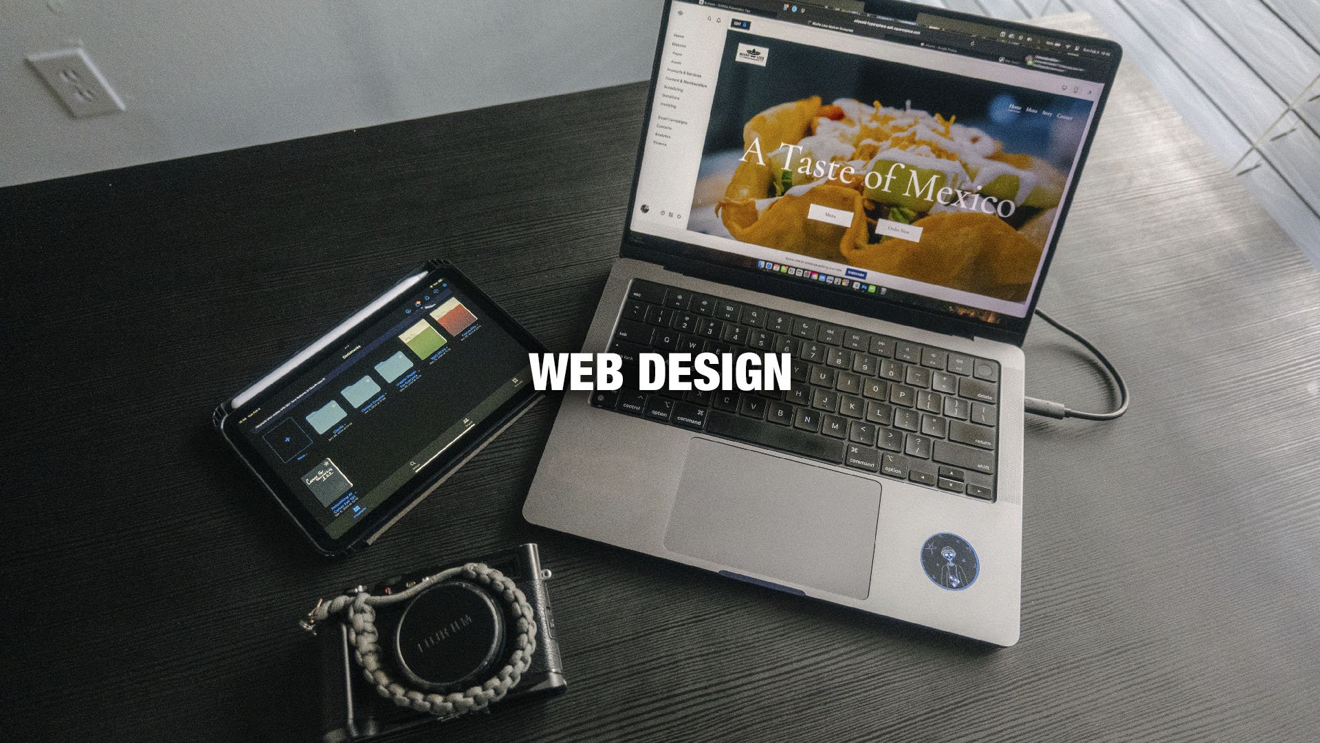 A laptop displaying a website titled "A Taste of Mexico," a tablet with design tools, and a digital camera on a dark wooden desk, with the words "WEB DESIGN" overlaid.