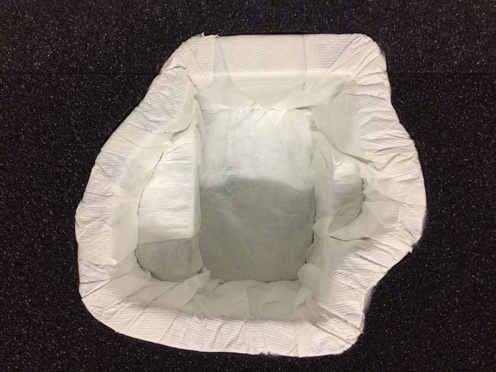 Empty white disposable diaper placed on a black surface.
