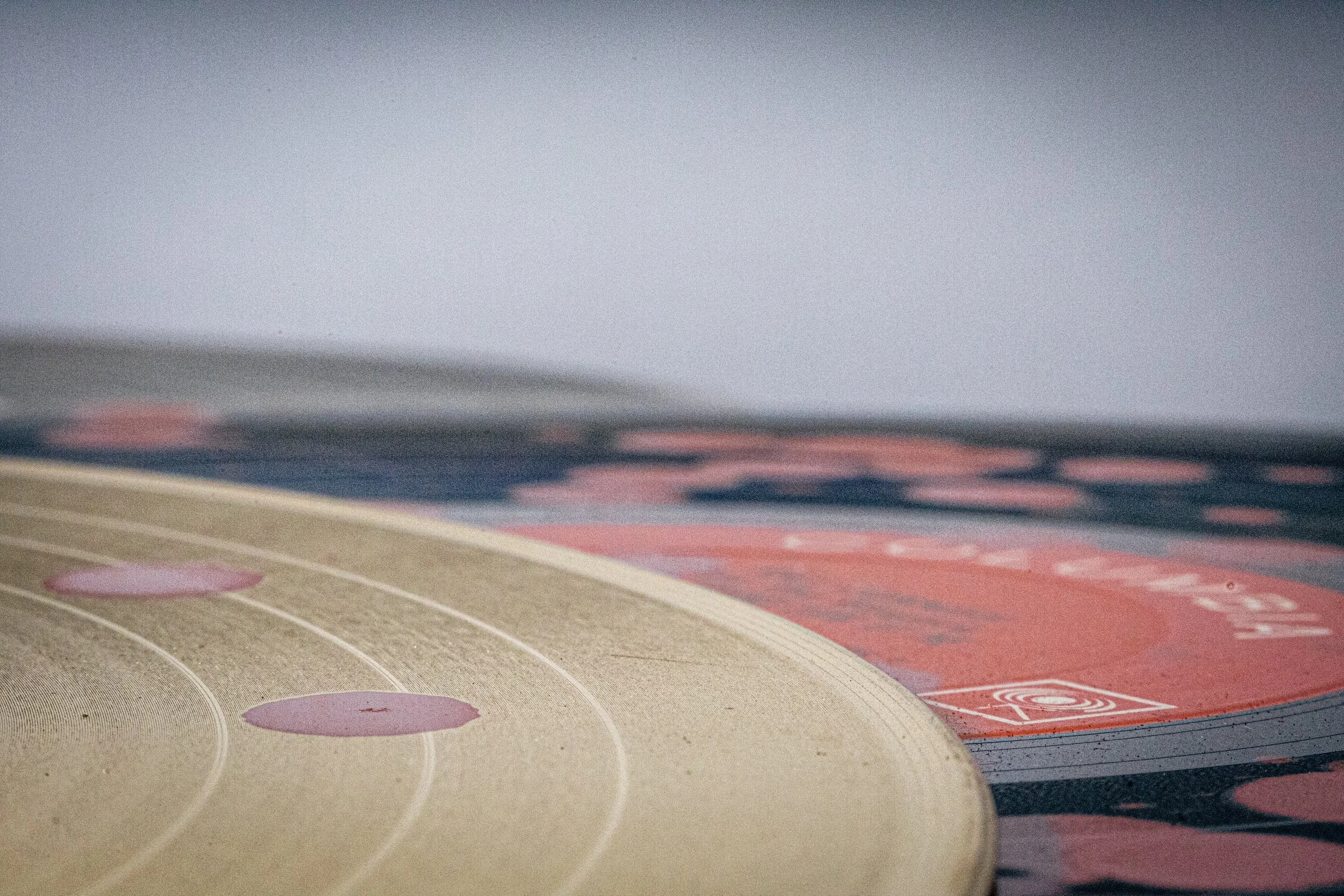 Close-up of stacked vinyl records with red paint splattered on a gold record and a black record with a red inlay label.