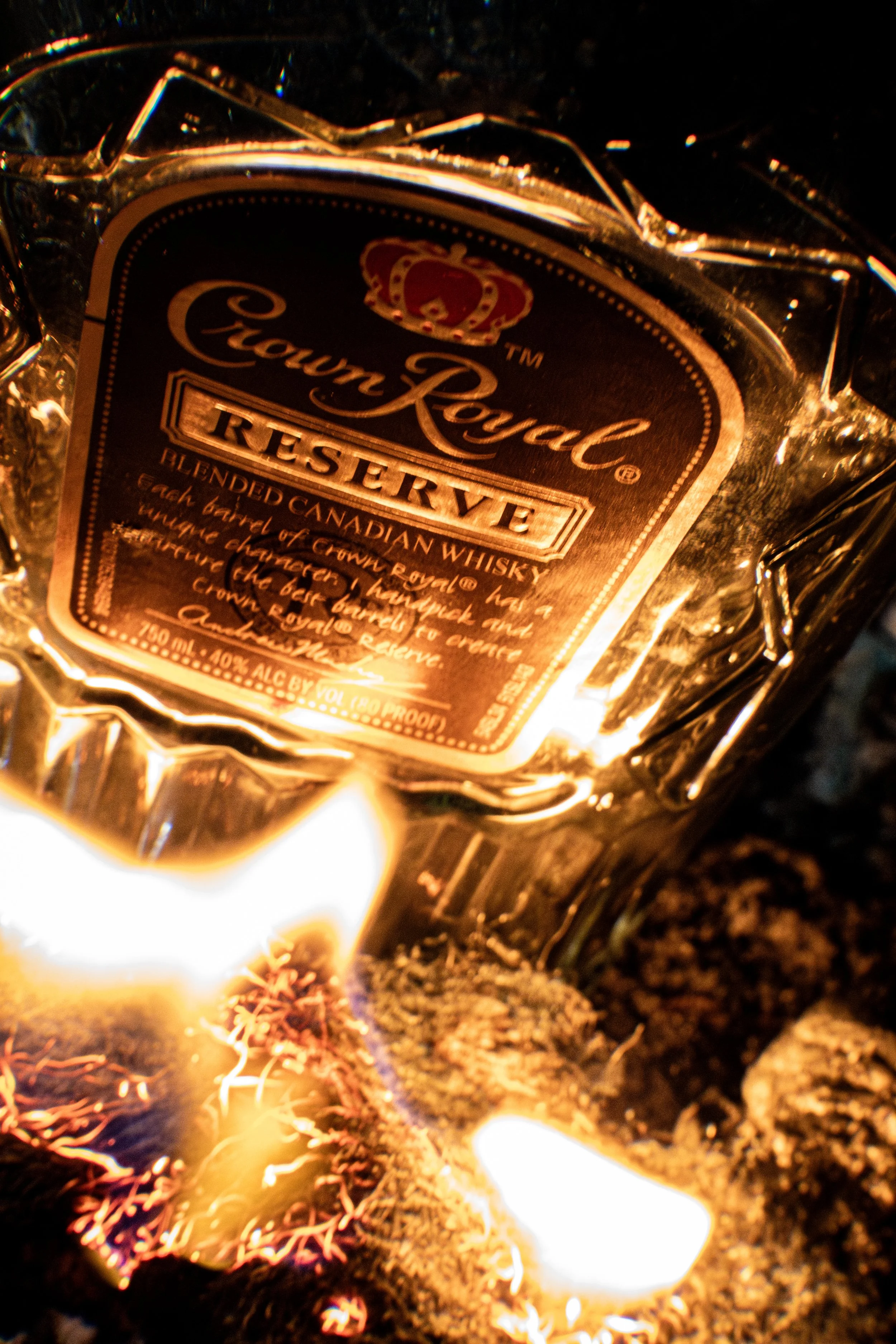 Bottle of Crown Royal Reserve blended Canadian whisky on fire with flames surrounding the bottle.