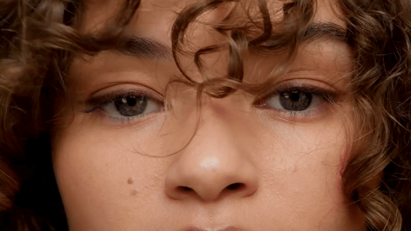 Close-up of a person with curly hair and blue eyes.