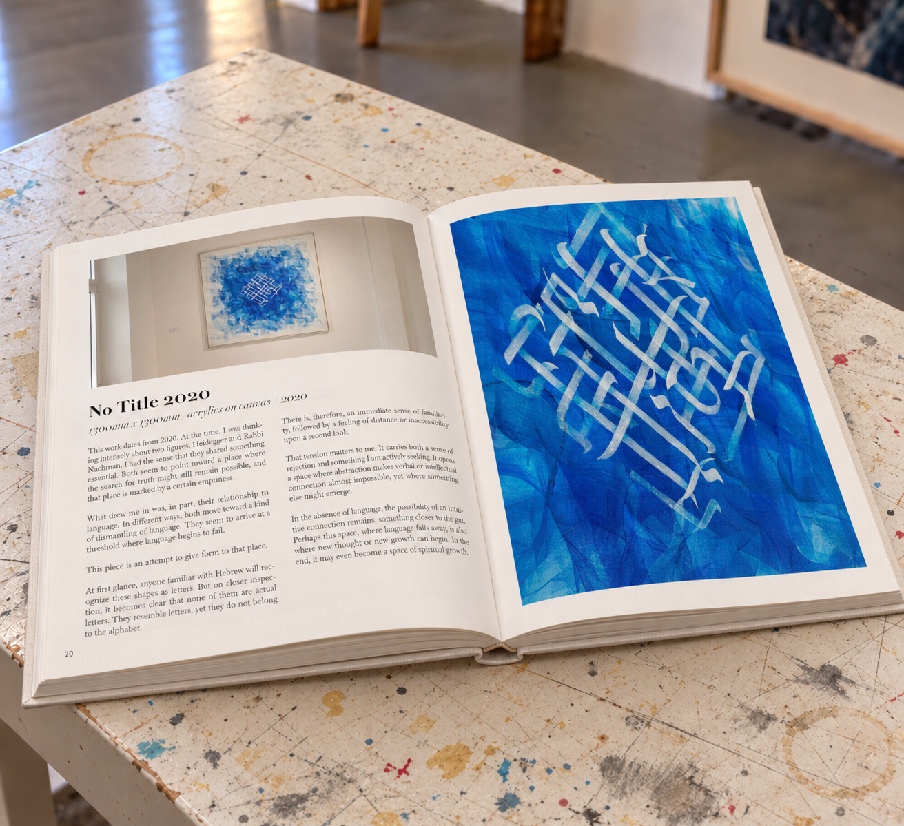 The catalogue Gabriel Wolff: Zurückgeworfenheit lying open on a worktable, showing text and a full-page image of a blue painting with a white lattice of letter forms.