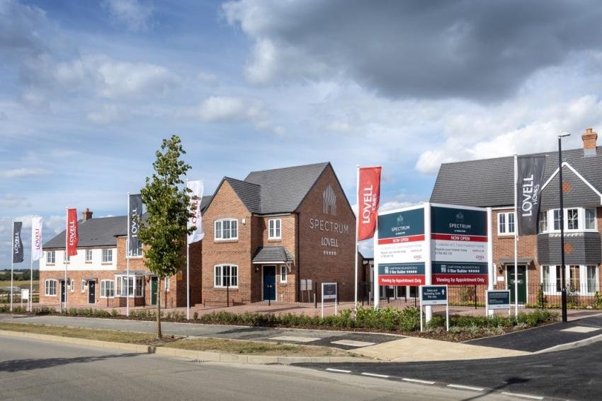 Newly built housing estate with trees and lovell flags and signage