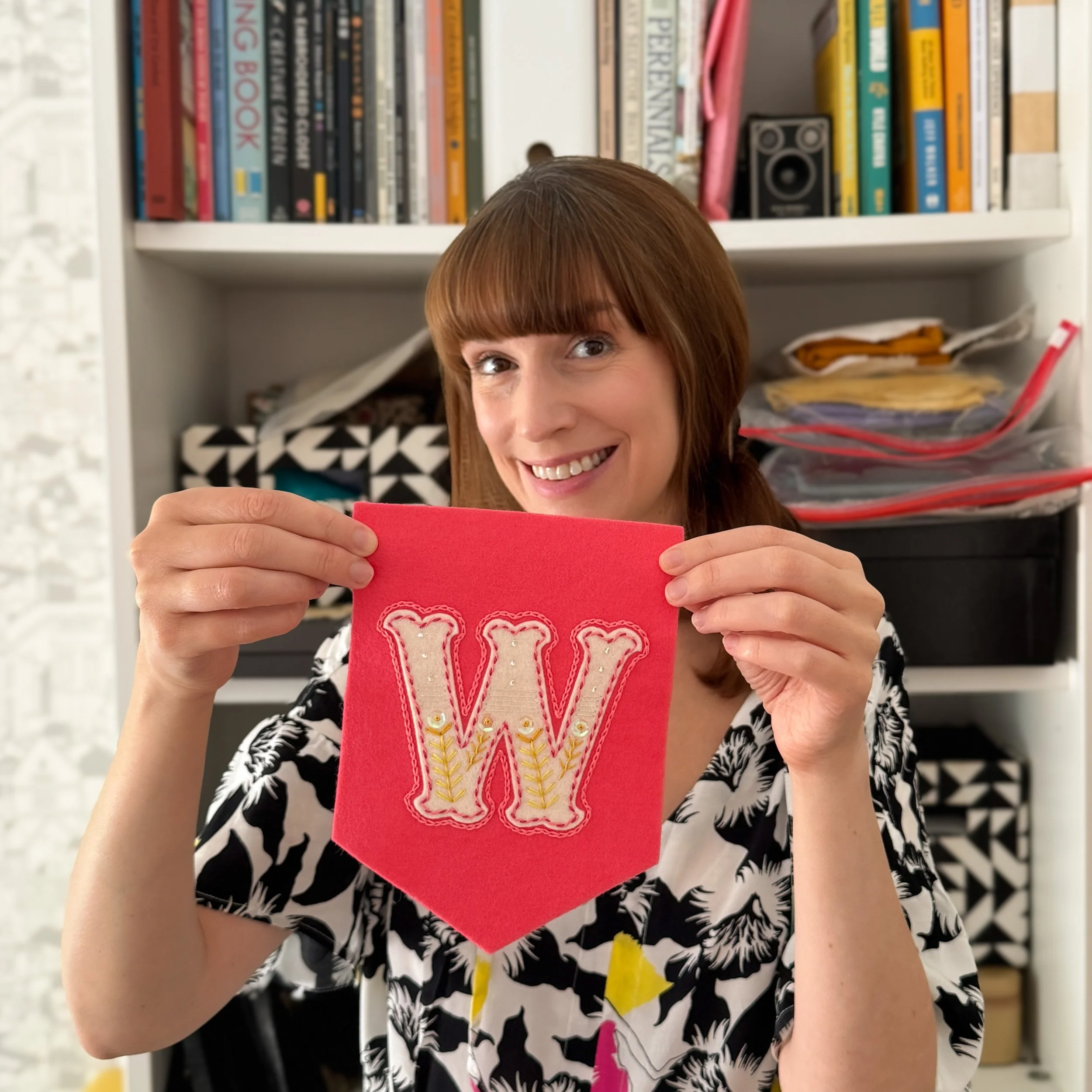 Tamara, designer of The Hoop in Hand, is holding up an embroidered felt 'W' for workshops