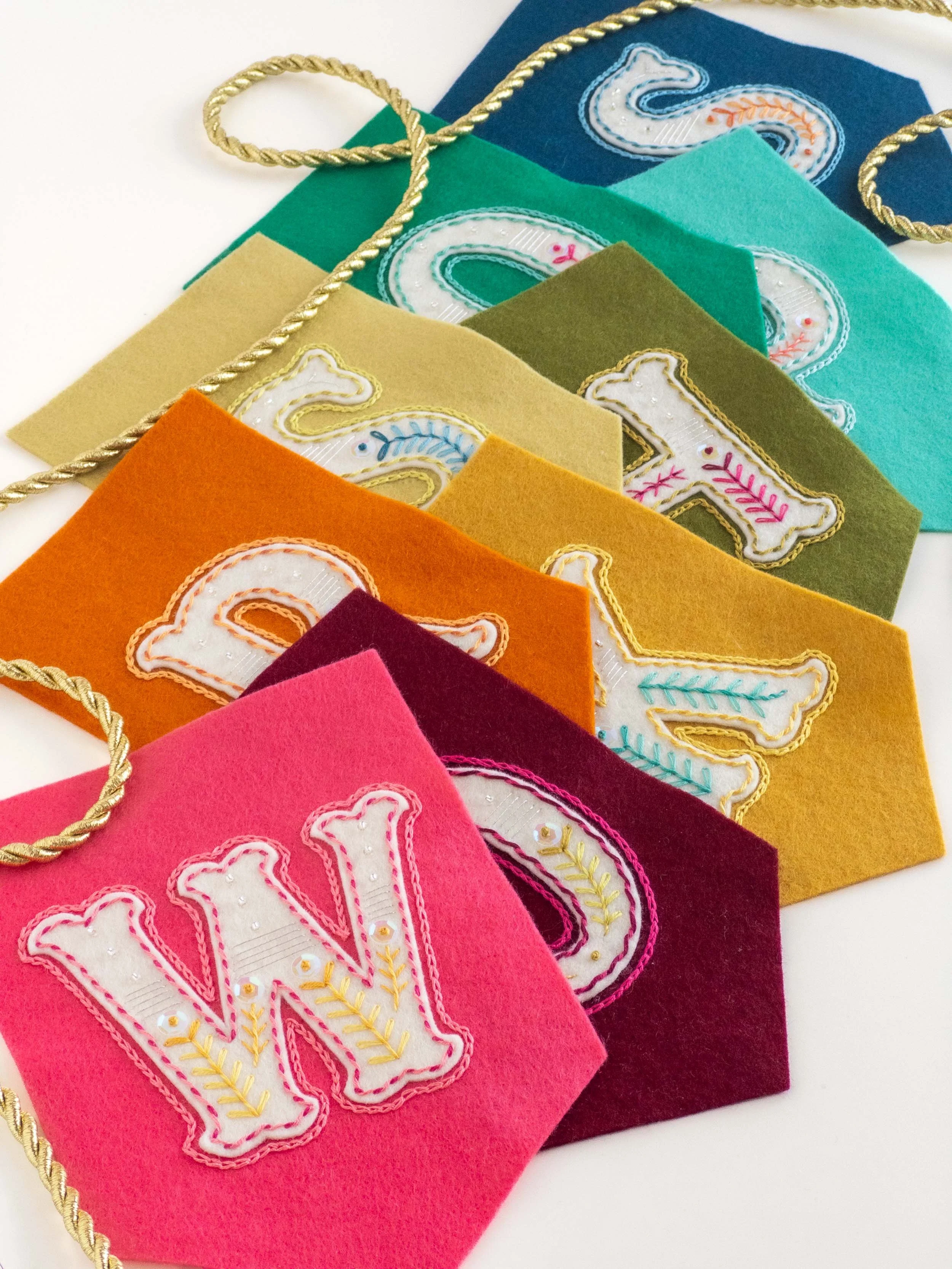Embroidered felt bunting in rainbow colours, spelling out the word 'workshops'.