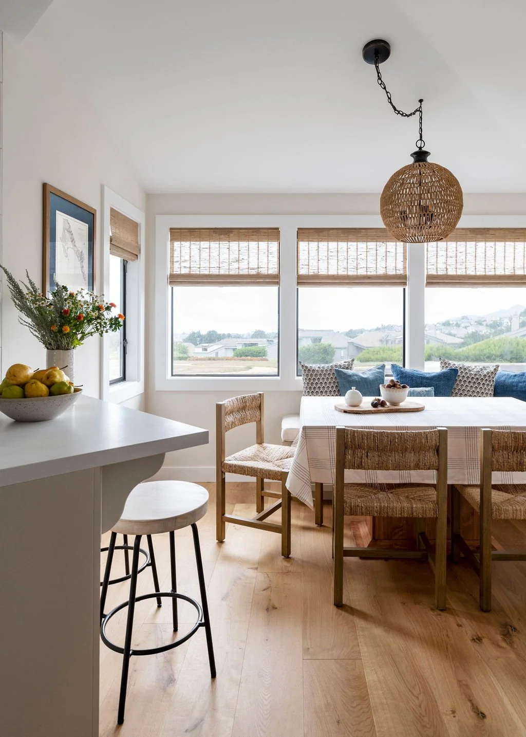 Light-filled dining area in the Bodega Bay project by Arntz Interiors featuring woven seating, natural wood floors, and coastal-inspired textures.