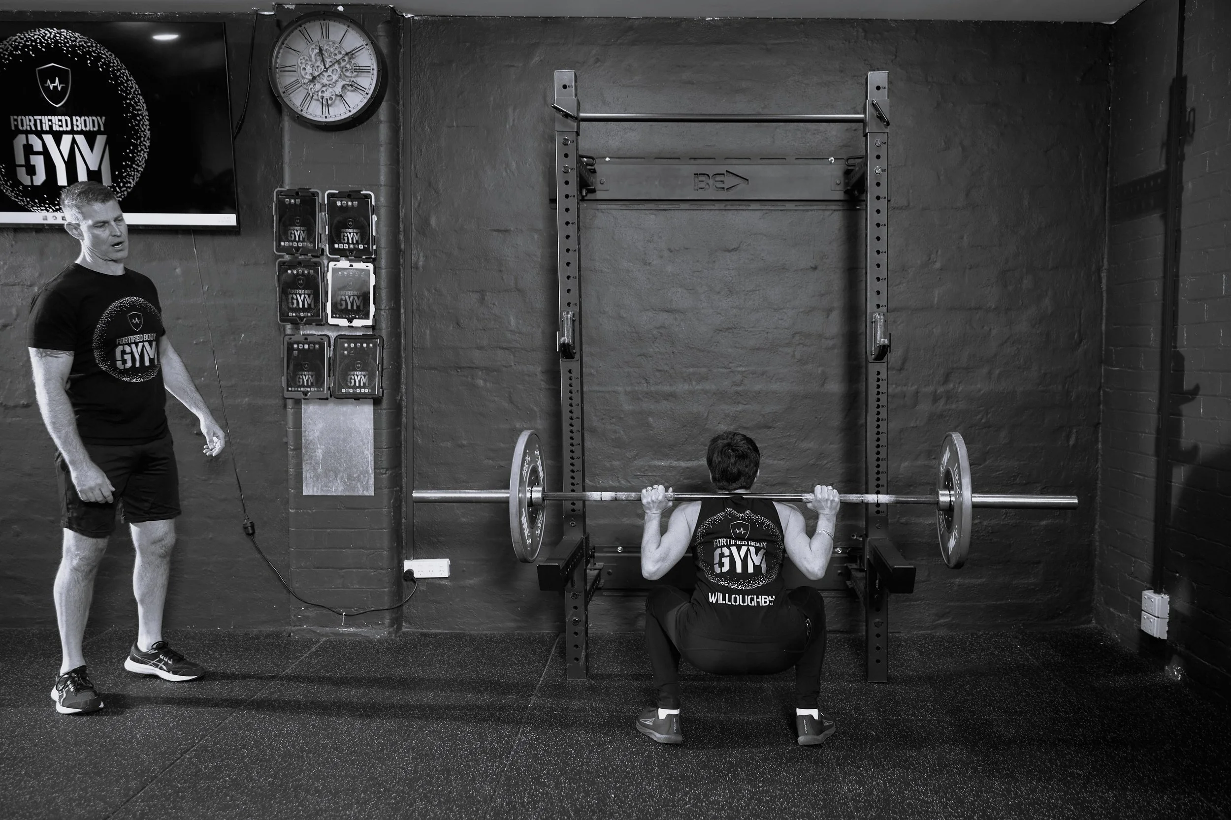 Coach guiding client through proper squat technique