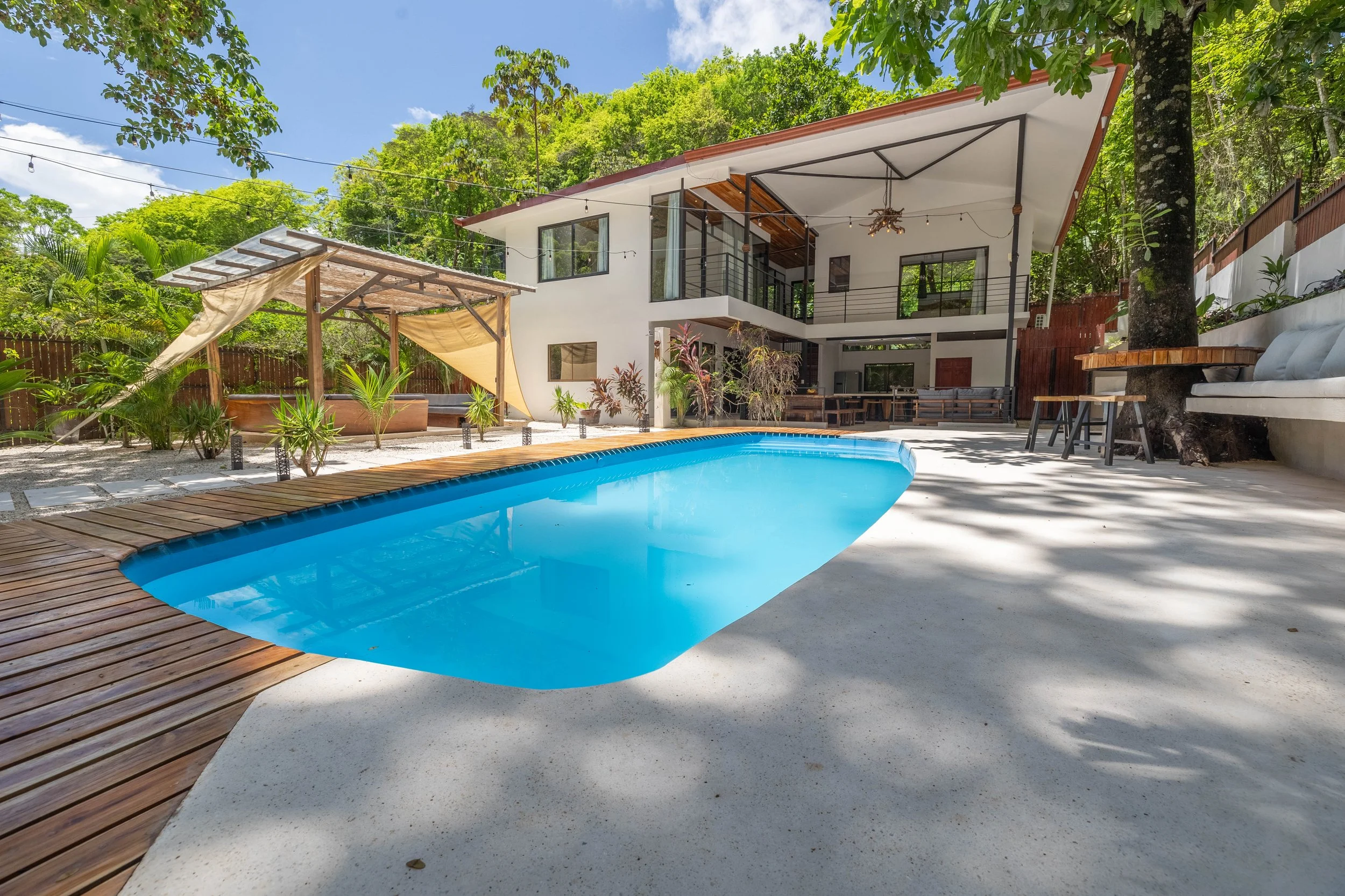Modern villa with a backyard pool, surrounded by greenery and outdoor seating areas.
