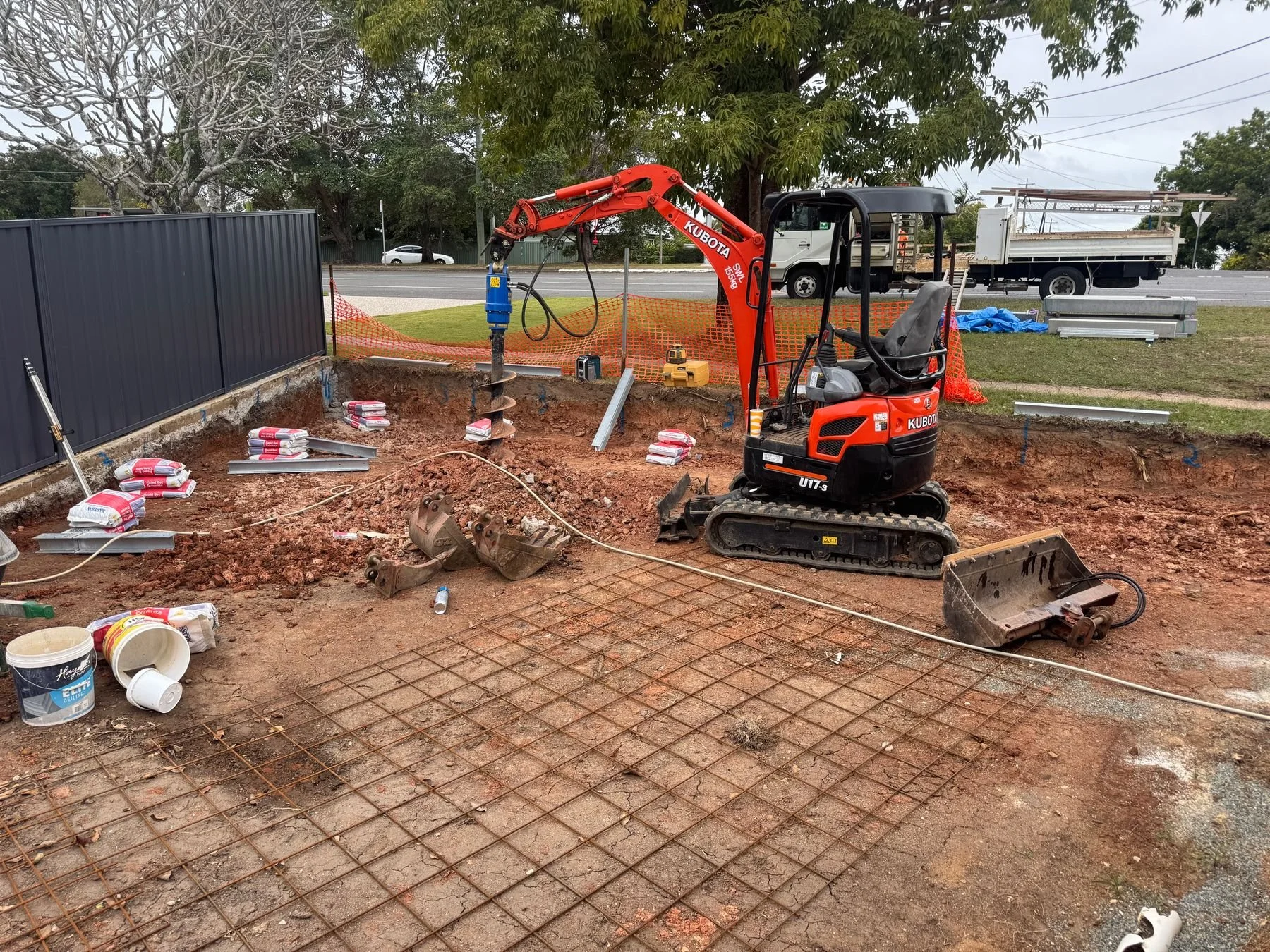 Excavator with post-hole auger and earthmoving attachments