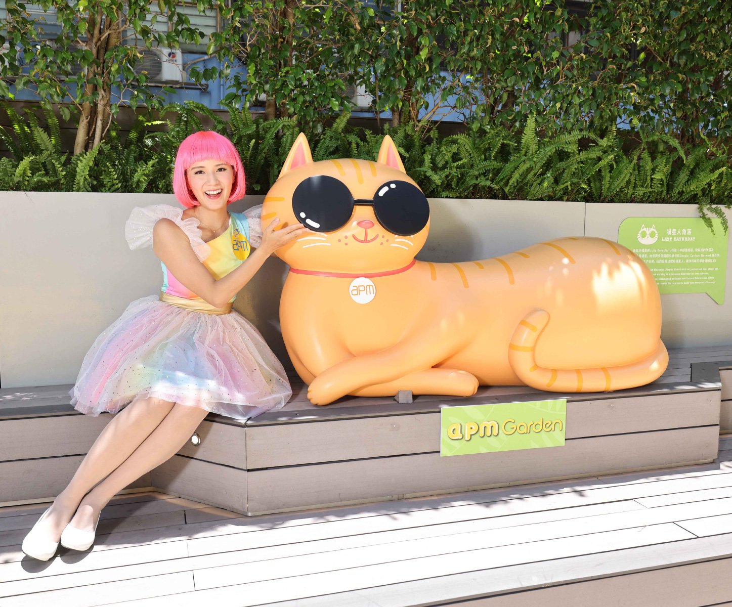 Photo of woman posing with 3D orange cat sculpture wearing sunglasses at APM Mall