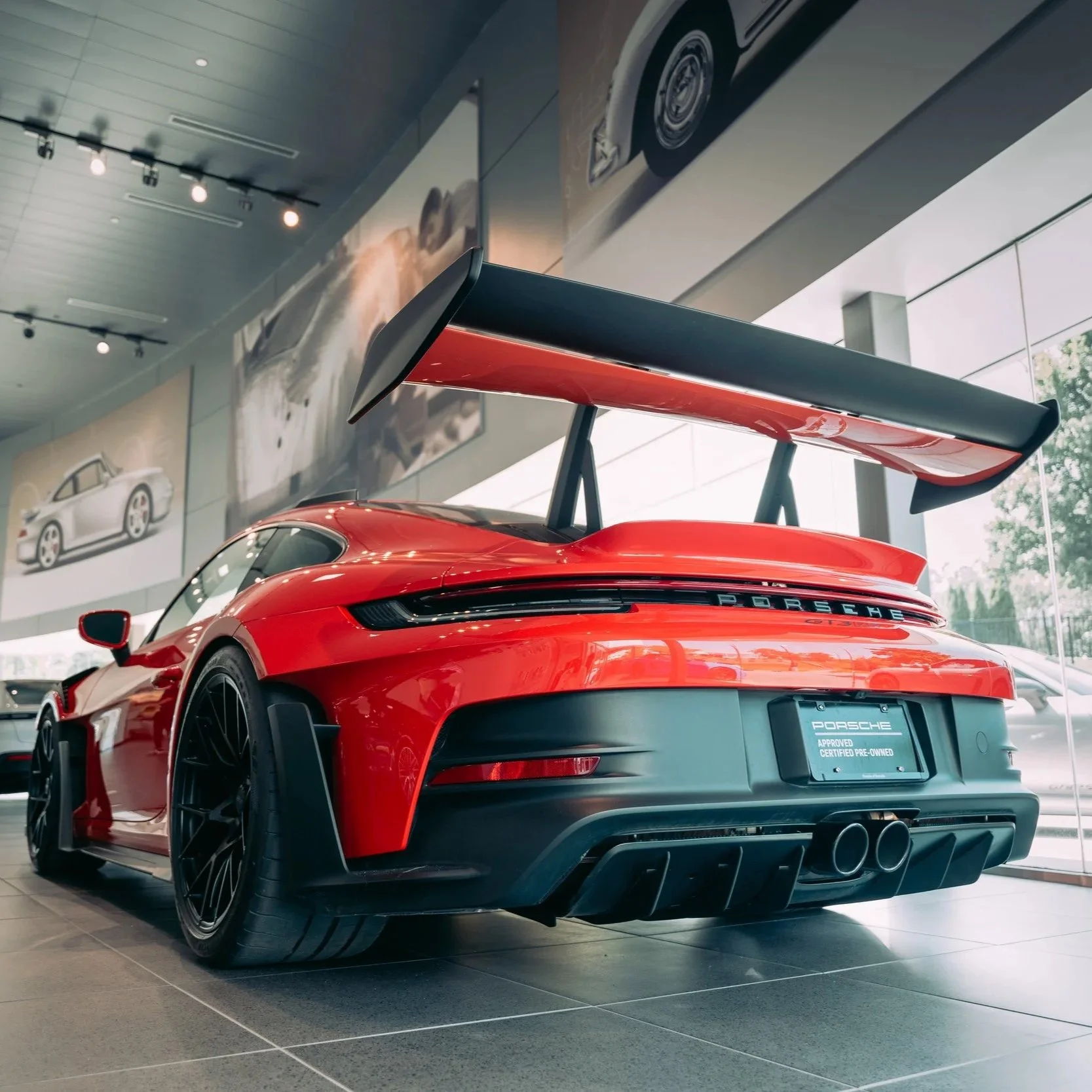 Red Porsche sports car with a large rear spoiler on display in a showroom.