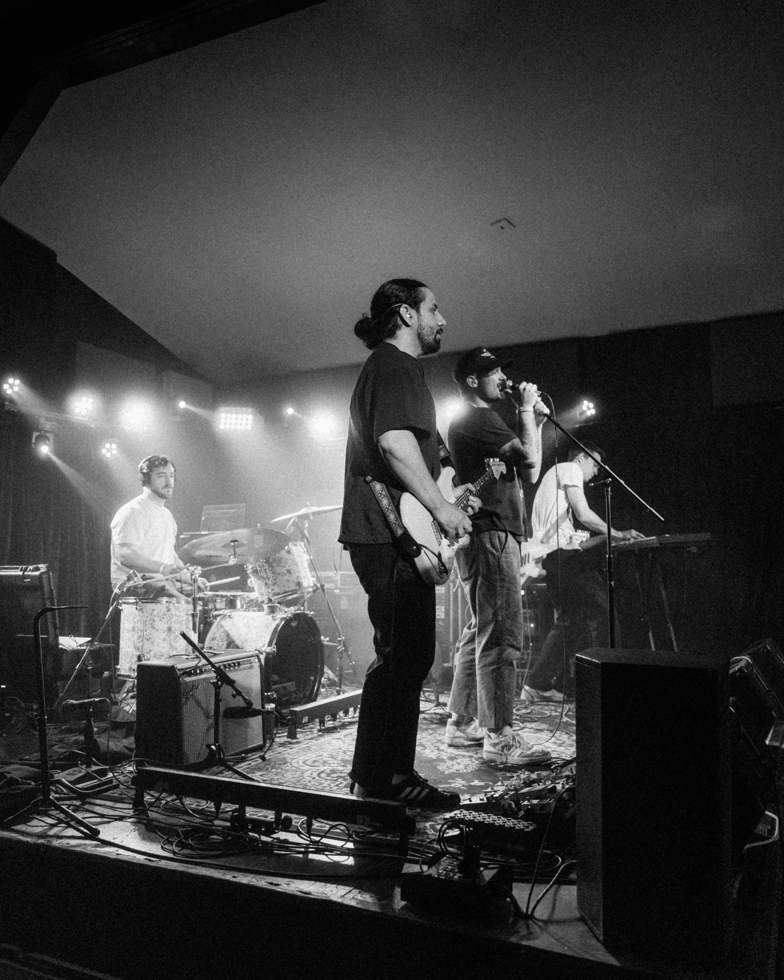 A band performing live on stage with four members playing instruments and singing.