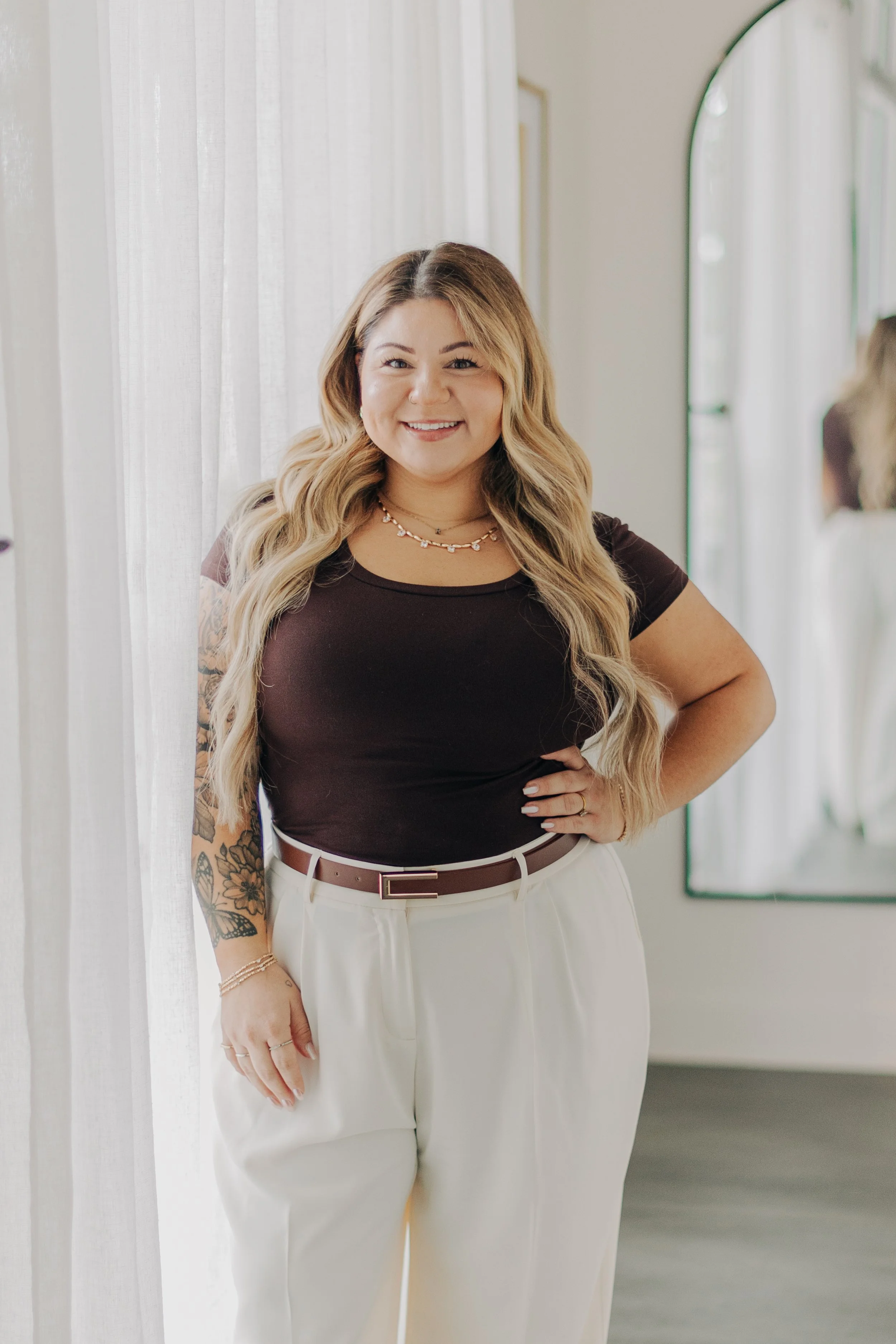 Woman leaning on a white counter in an interior setting with blurred decor in the background.