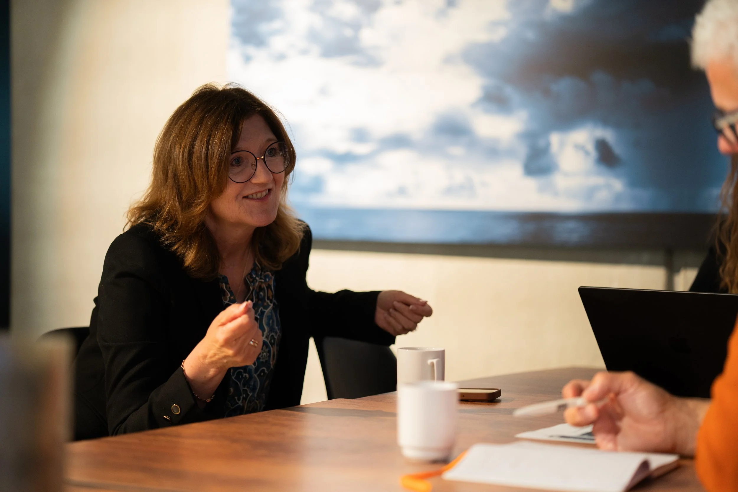 dame som diskuterer rundt et bord med kaffekopper.