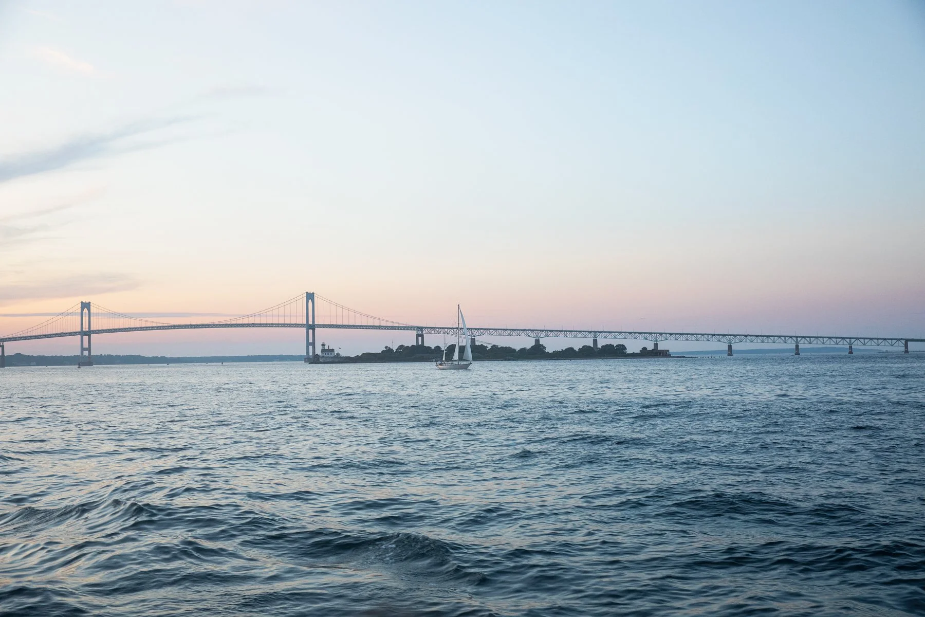 Lone sail boat on the water in Newport, Rhode Island at dusk.