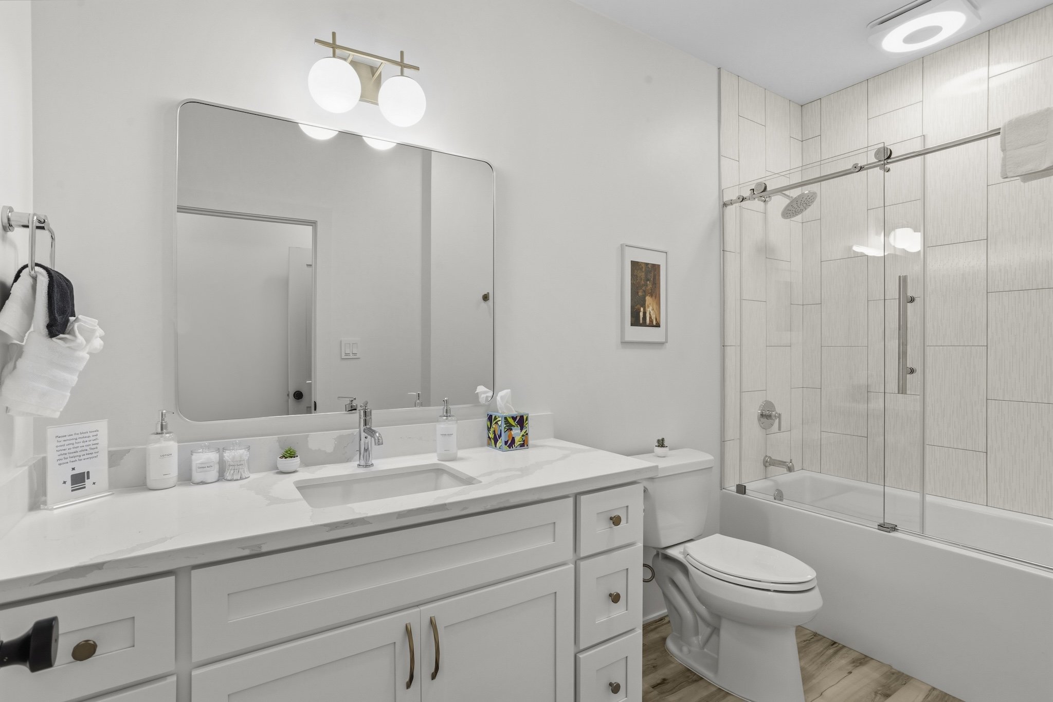 A modern bathroom with a white vanity, large mirror, and a shower with glass sliding doors.