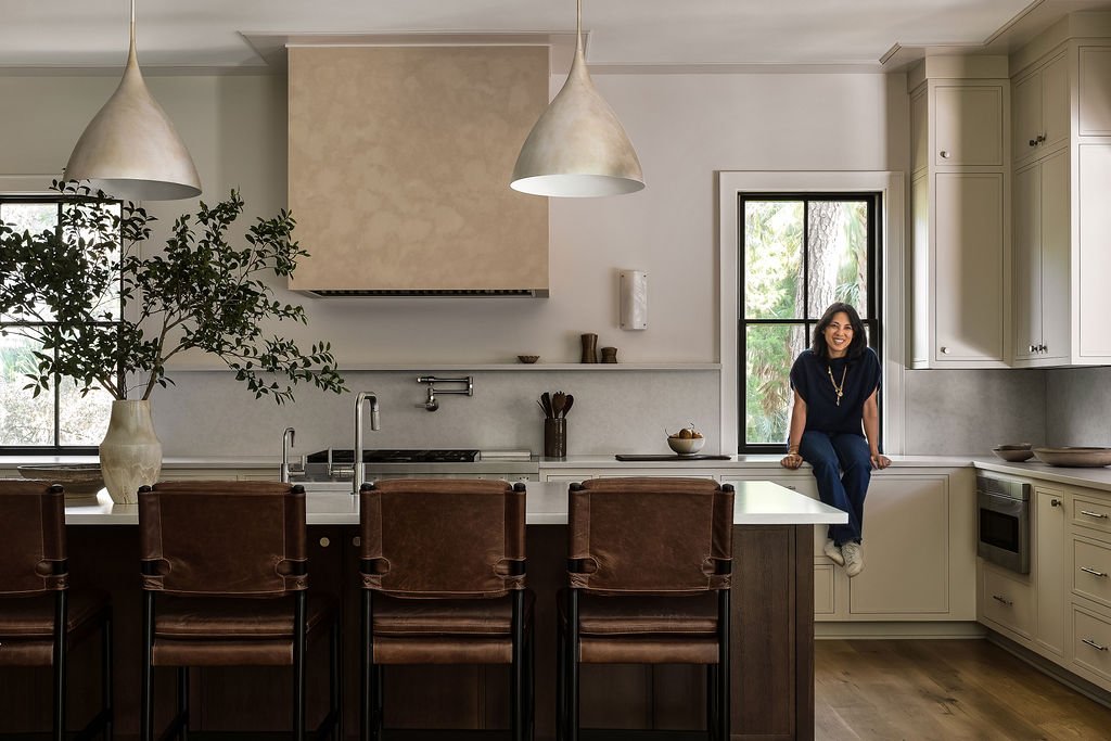 Modern white kitchen with a center island, stainless steel refrigerator, white cabinets, subway tile backsplash, and pendant lighting.