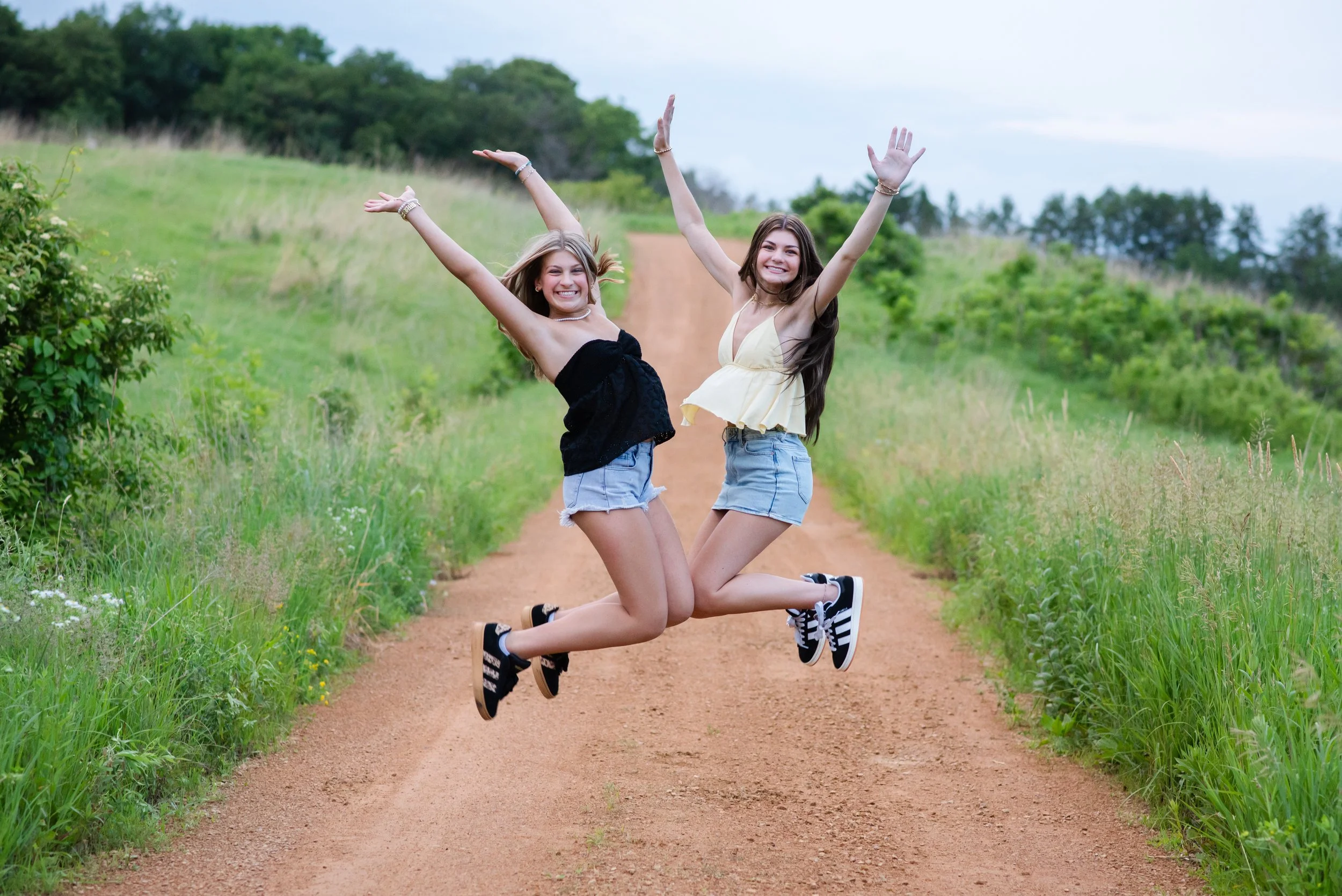two teenage girls jumping on a dirt path