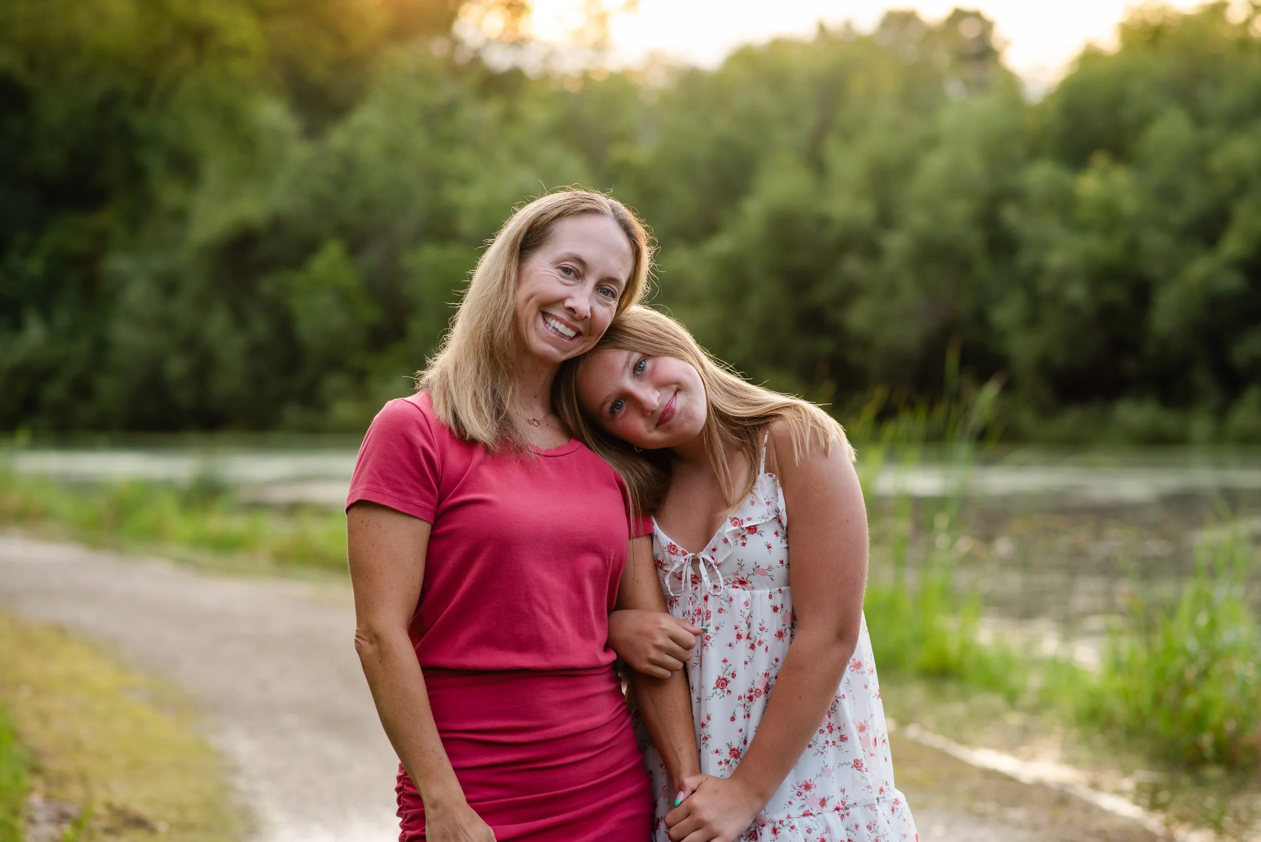mother and daughter hugging in front of a pond
