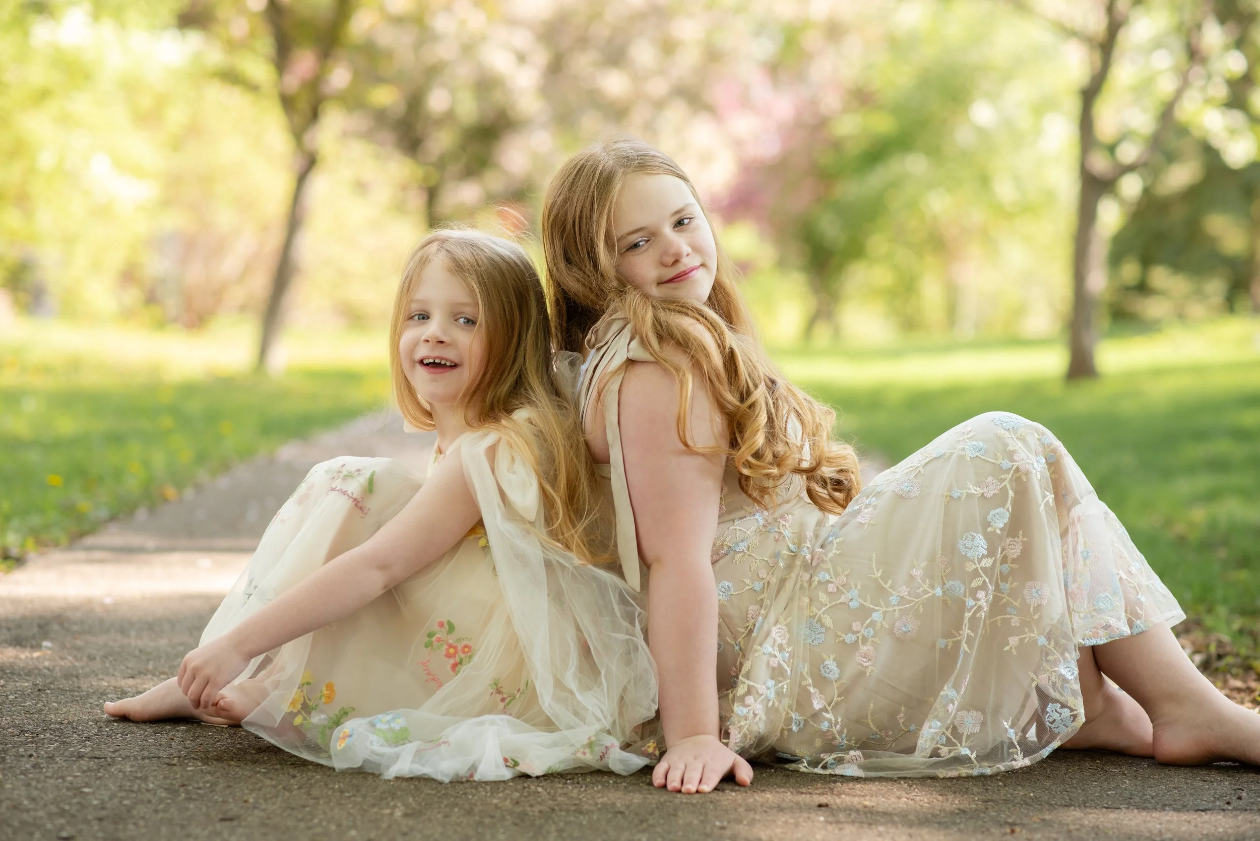 two young girls in dresses in the flowering trees