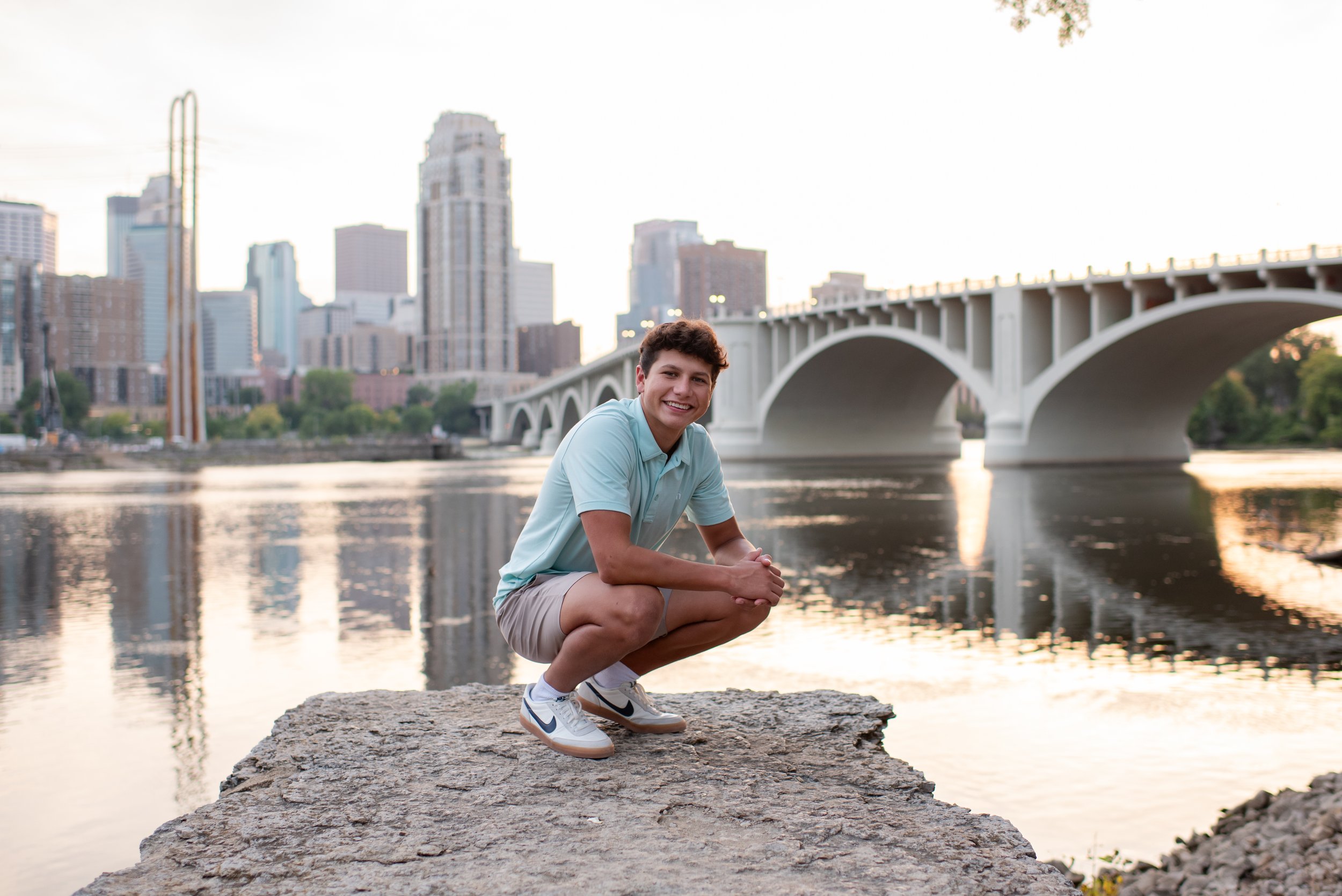 senior boy posing in front of bridge in downtown Minneapolis at sunset 