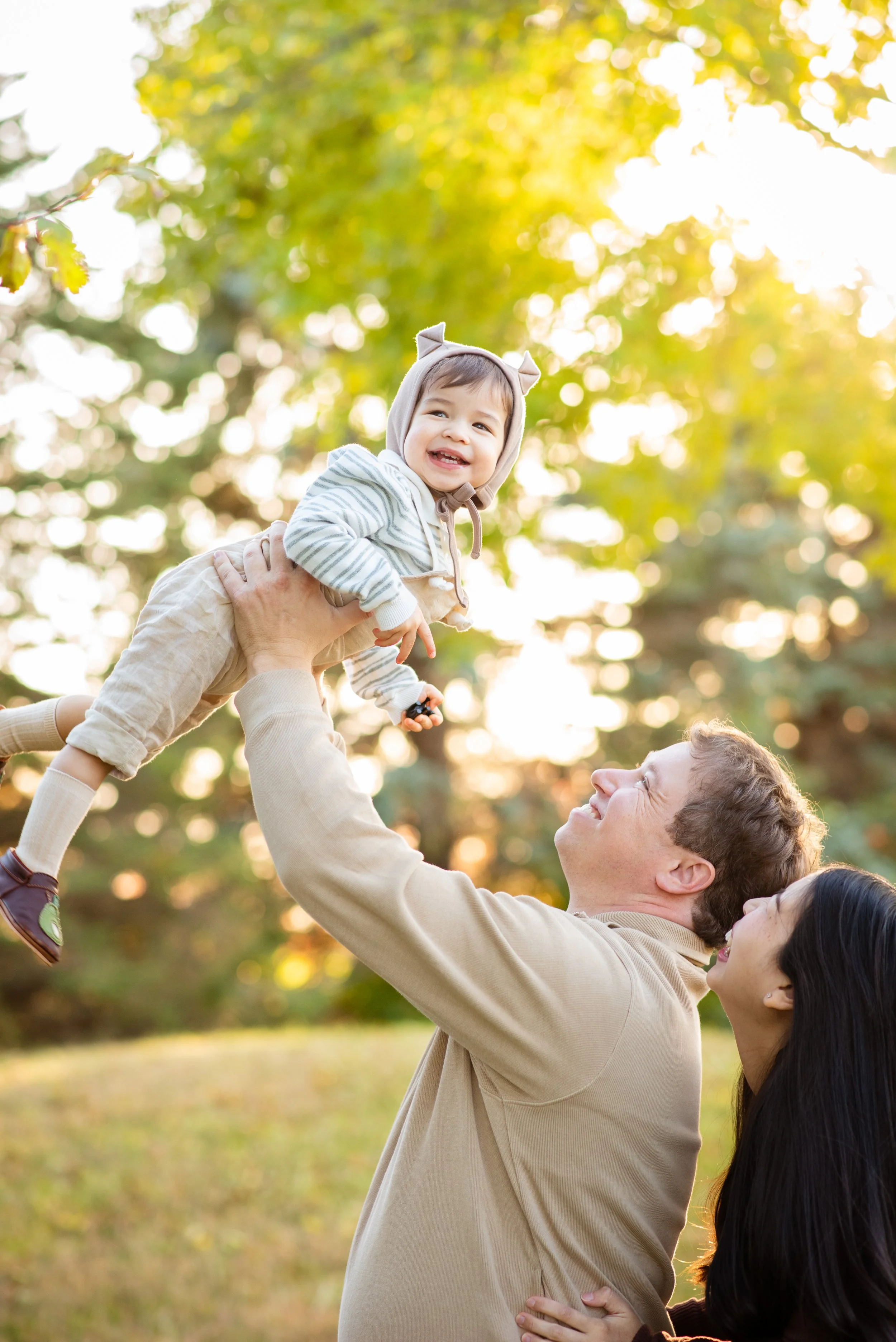Dad picking his little boy up while Mom laughs during fall family photo session