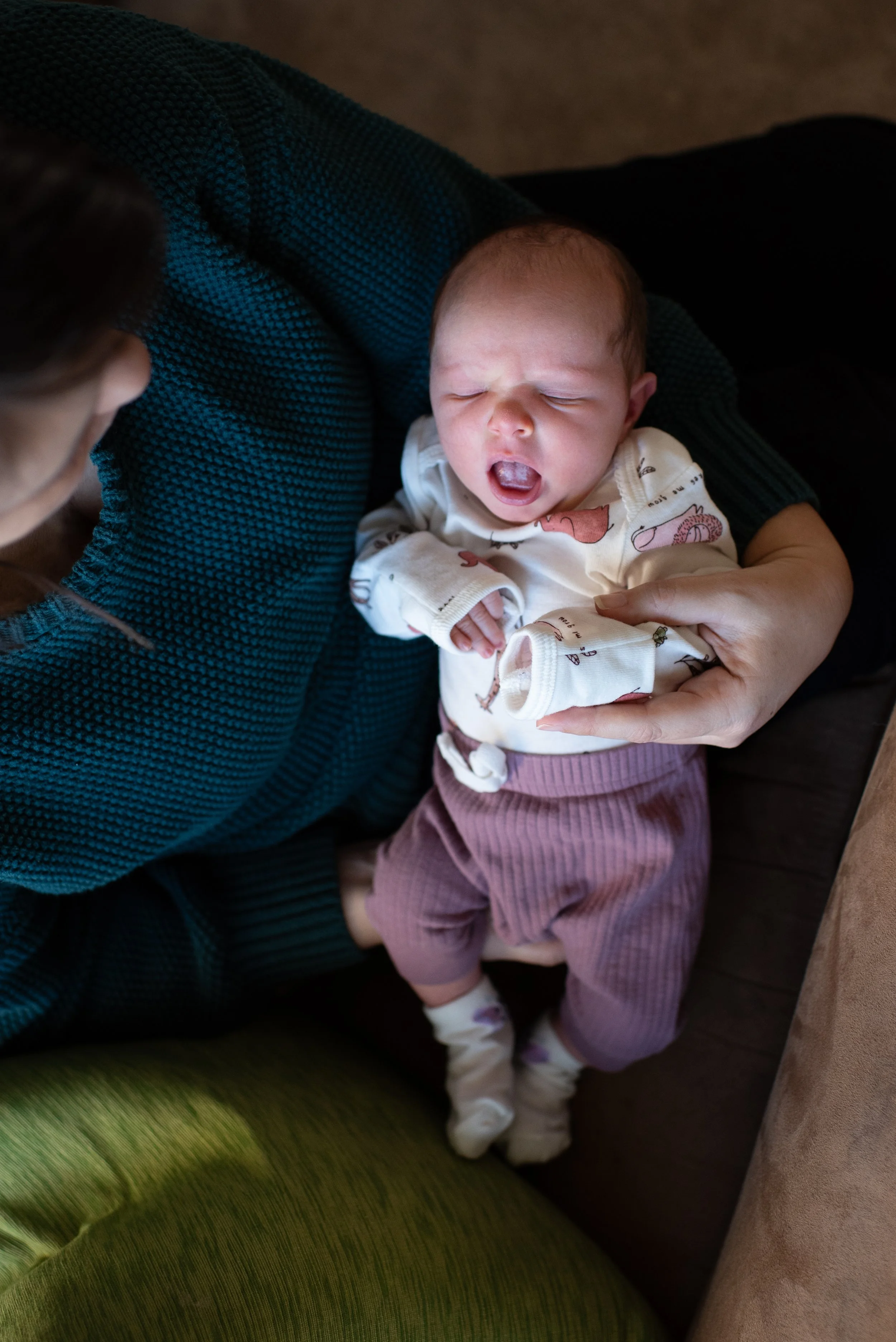 newborn baby yawning in mother's arms