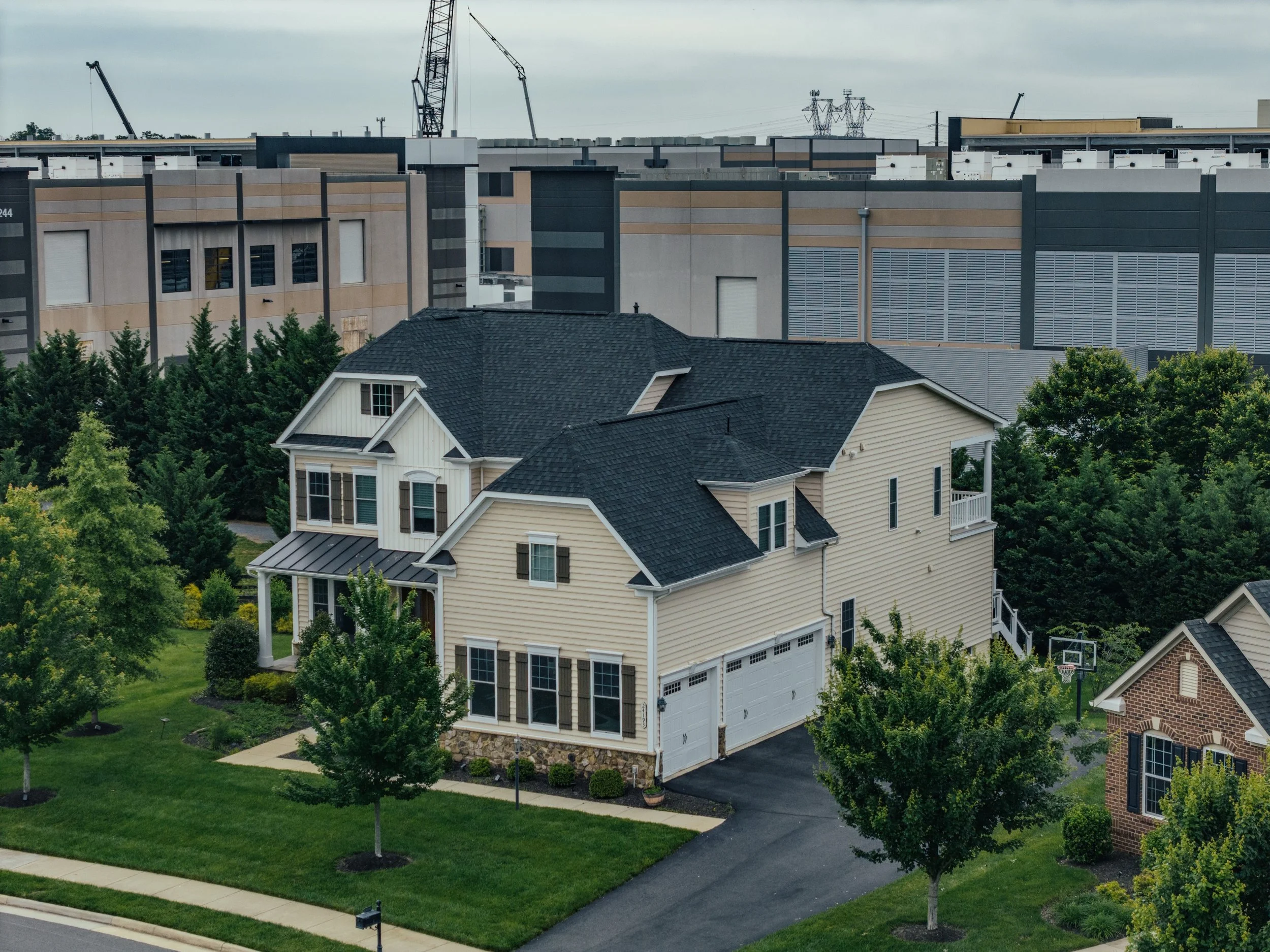 Photo of large house with three-door garage and a looming data center being built right up against the property line. Photo Credit: Steven Voss