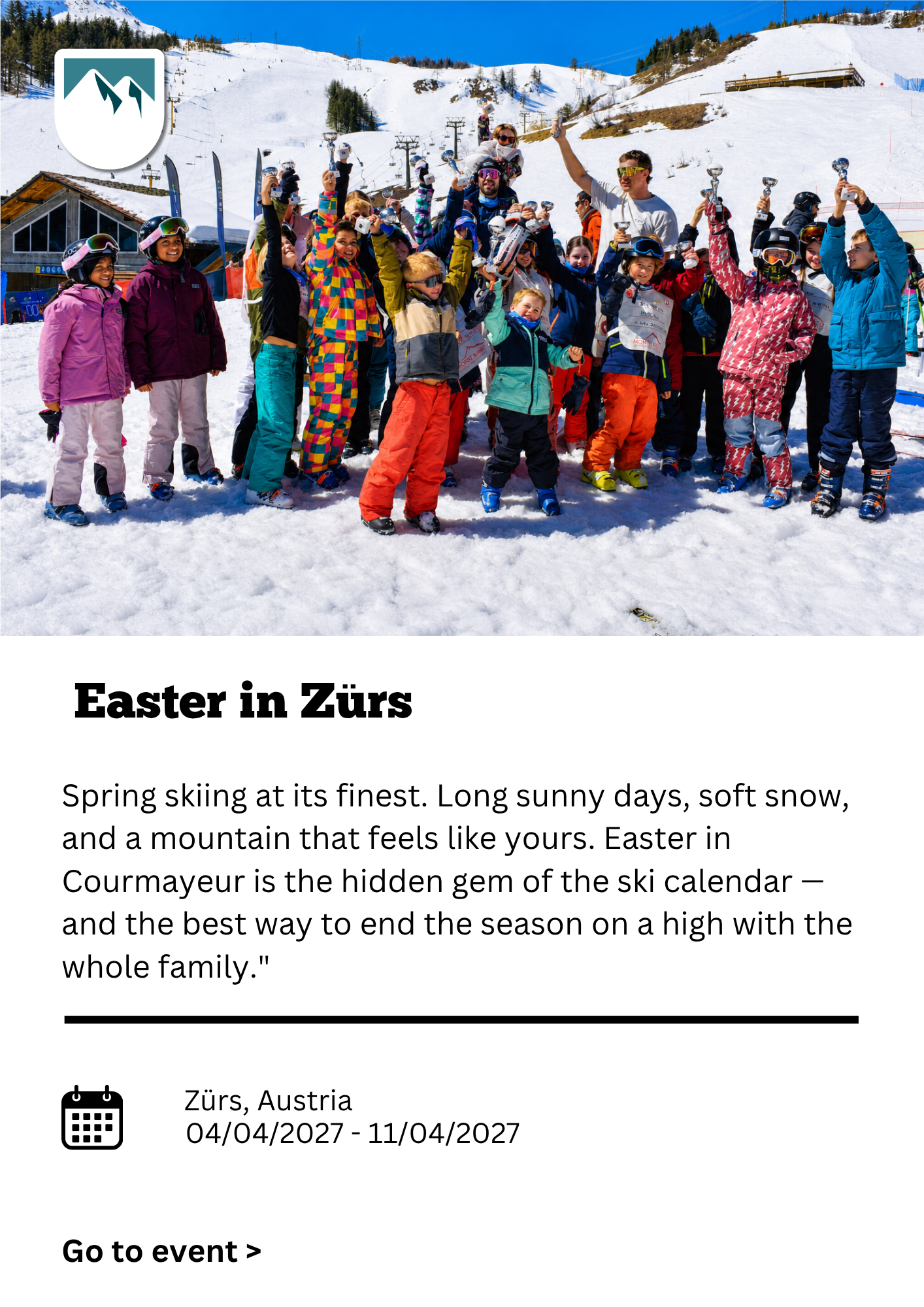 Group of children and adults in colorful ski gear celebrating on snow-covered ground at a ski resort in Zürs, Austria, with ski lifts and snowy mountains in the background.