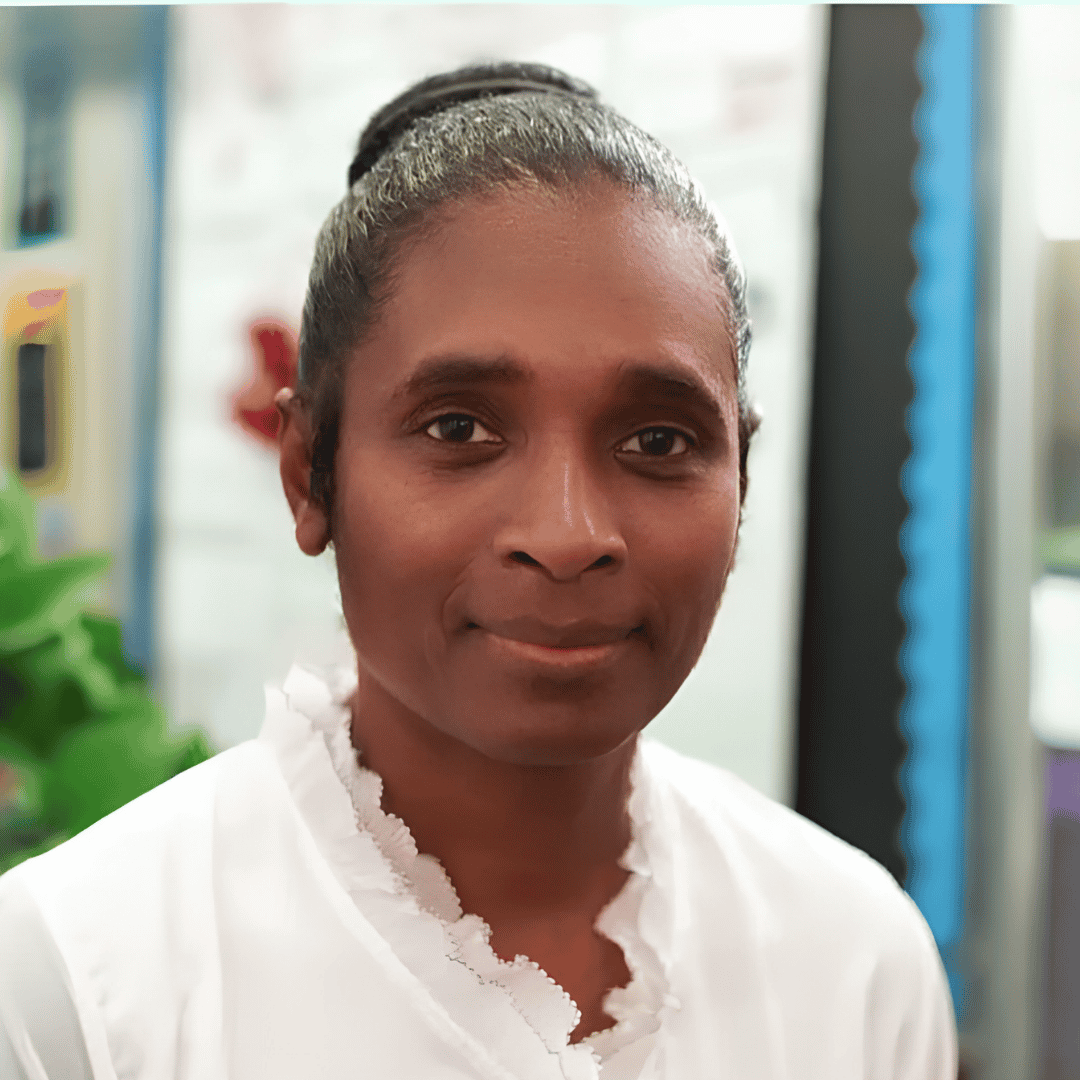 A woman with black hair pulled back wears a white ruffled top, standing indoors near greenery | ReEvolve Therapy