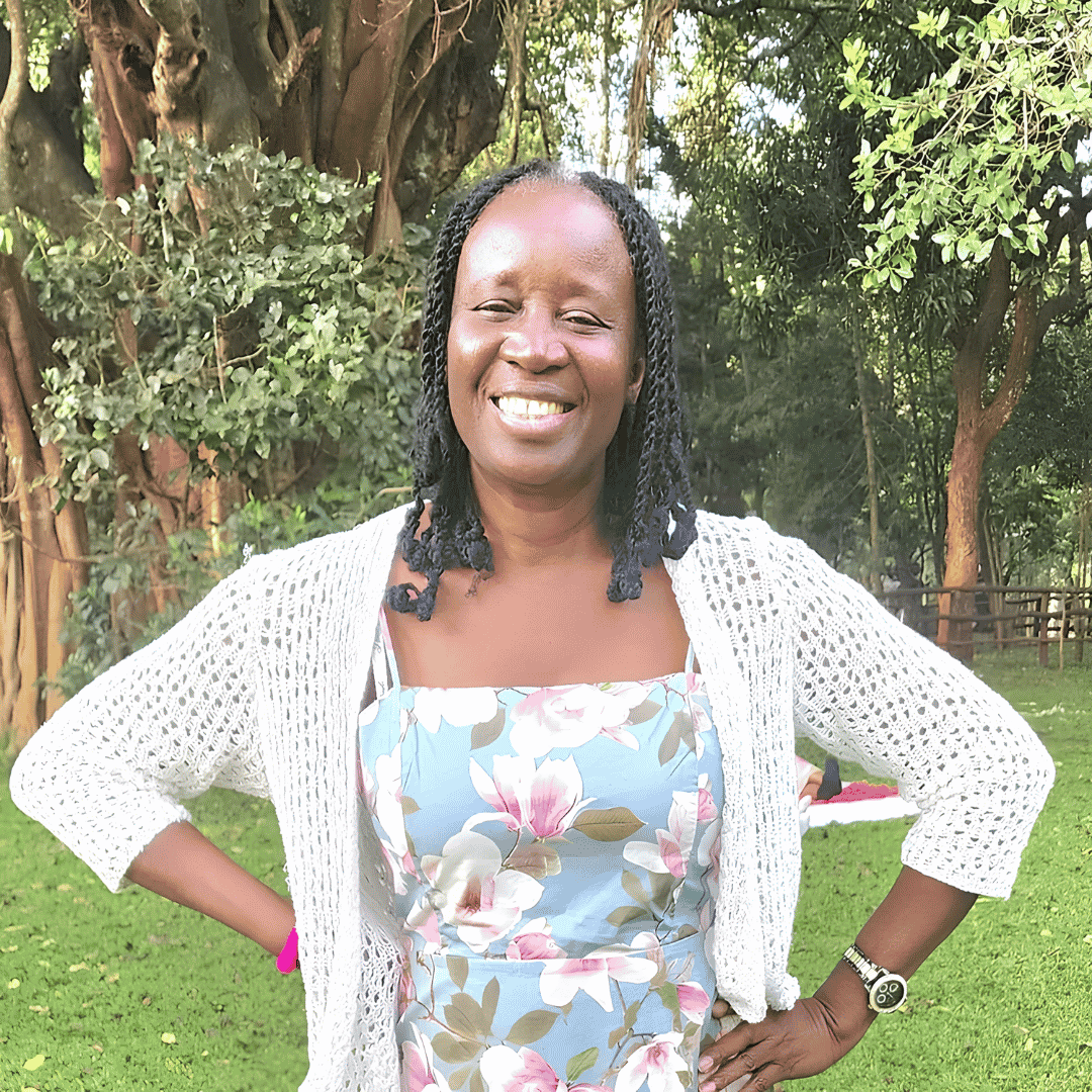 A smiling woman with braided hair wears a floral dress and a white cardigan, standing outdoors with trees in the background | ReEvolve Therapy