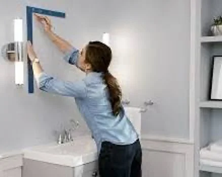 Woman hanging a picture on a gray wall bathroom