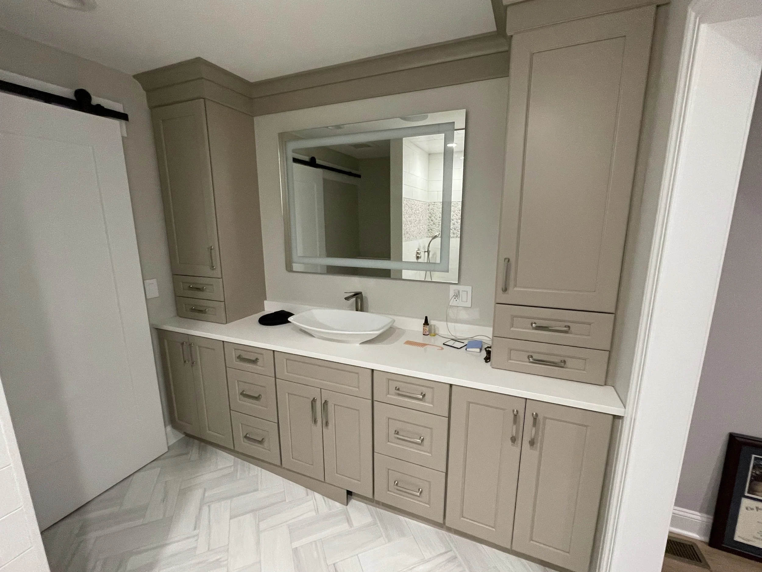 Bathroom vanity with a mirror, a bowl sink, beige cabinetry, and a white countertop.