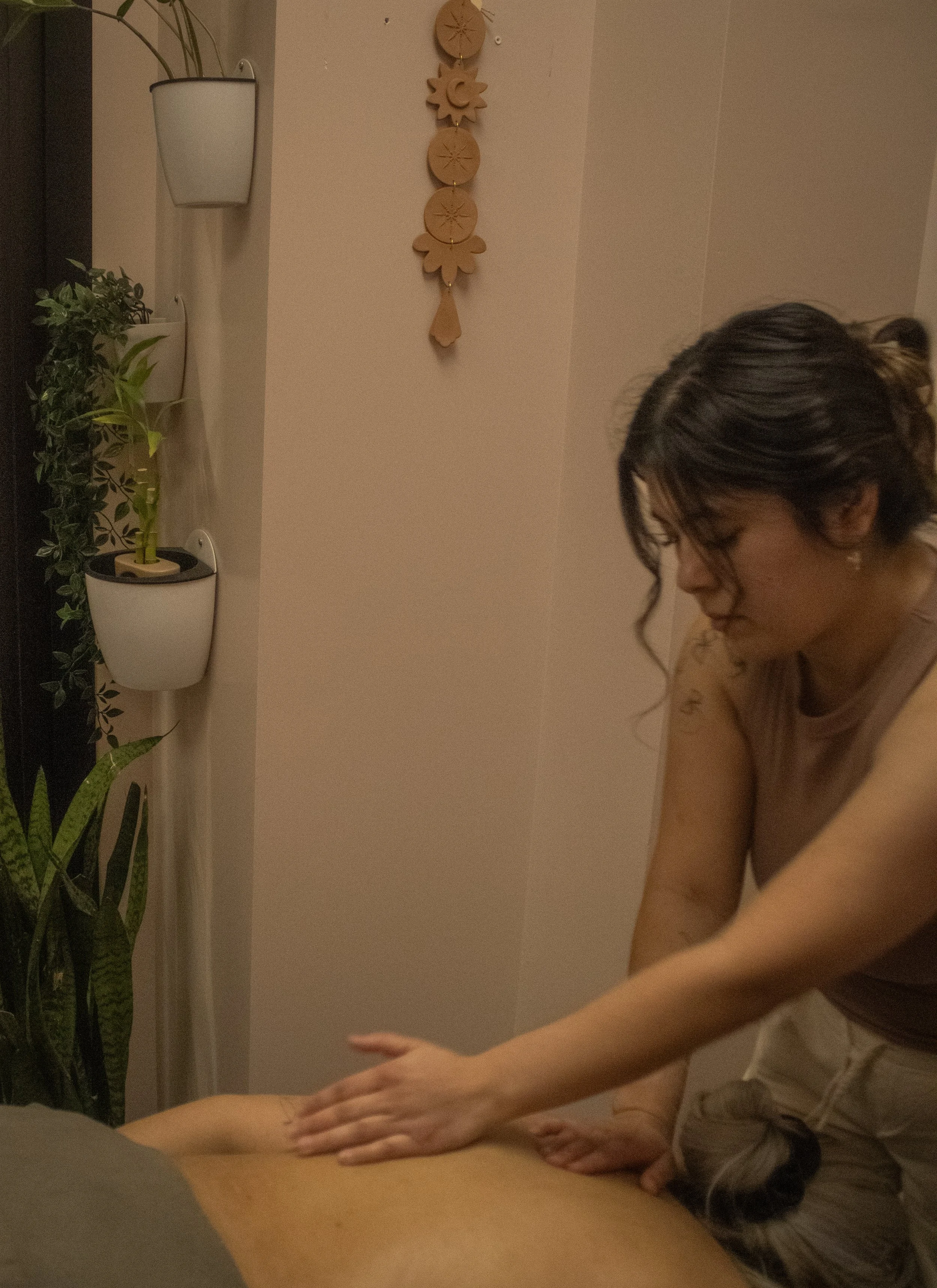 Person giving a massage in a room with plants and wall decor.