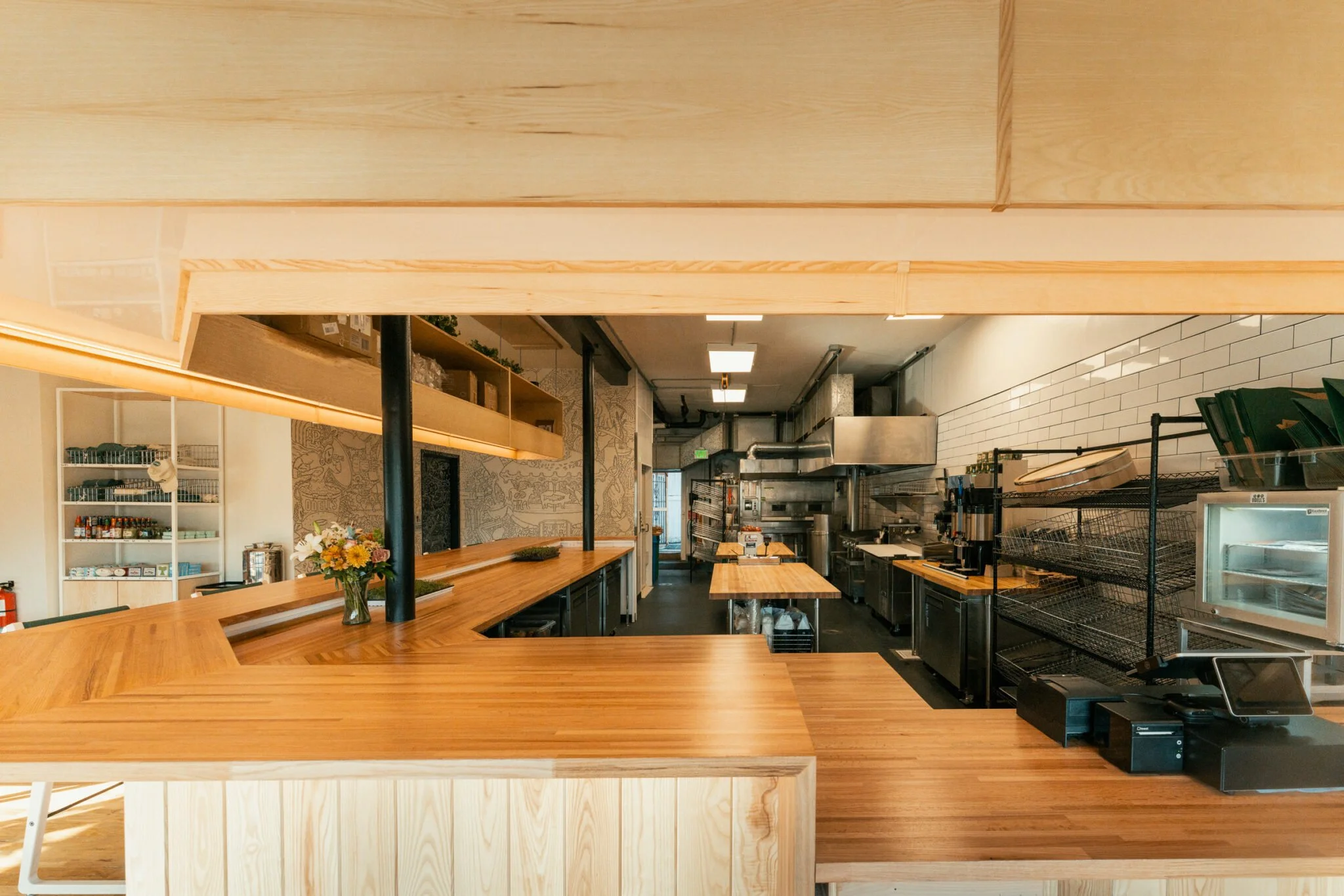 Empty restaurant kitchen with wooden countertops, industrial appliances, and shelving units.