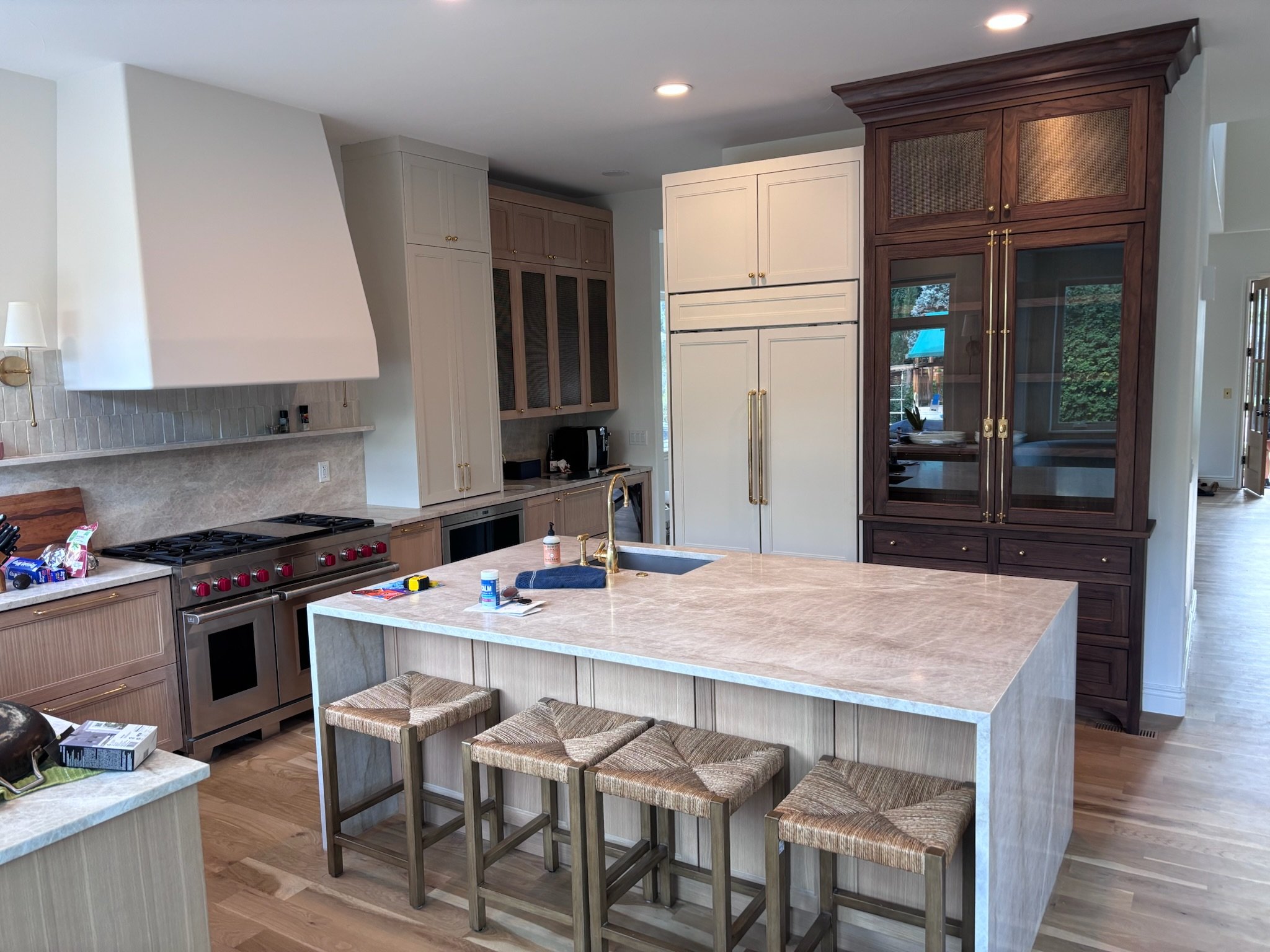 Modern kitchen with a large island, four stools, and a mix of white and dark wood cabinets.