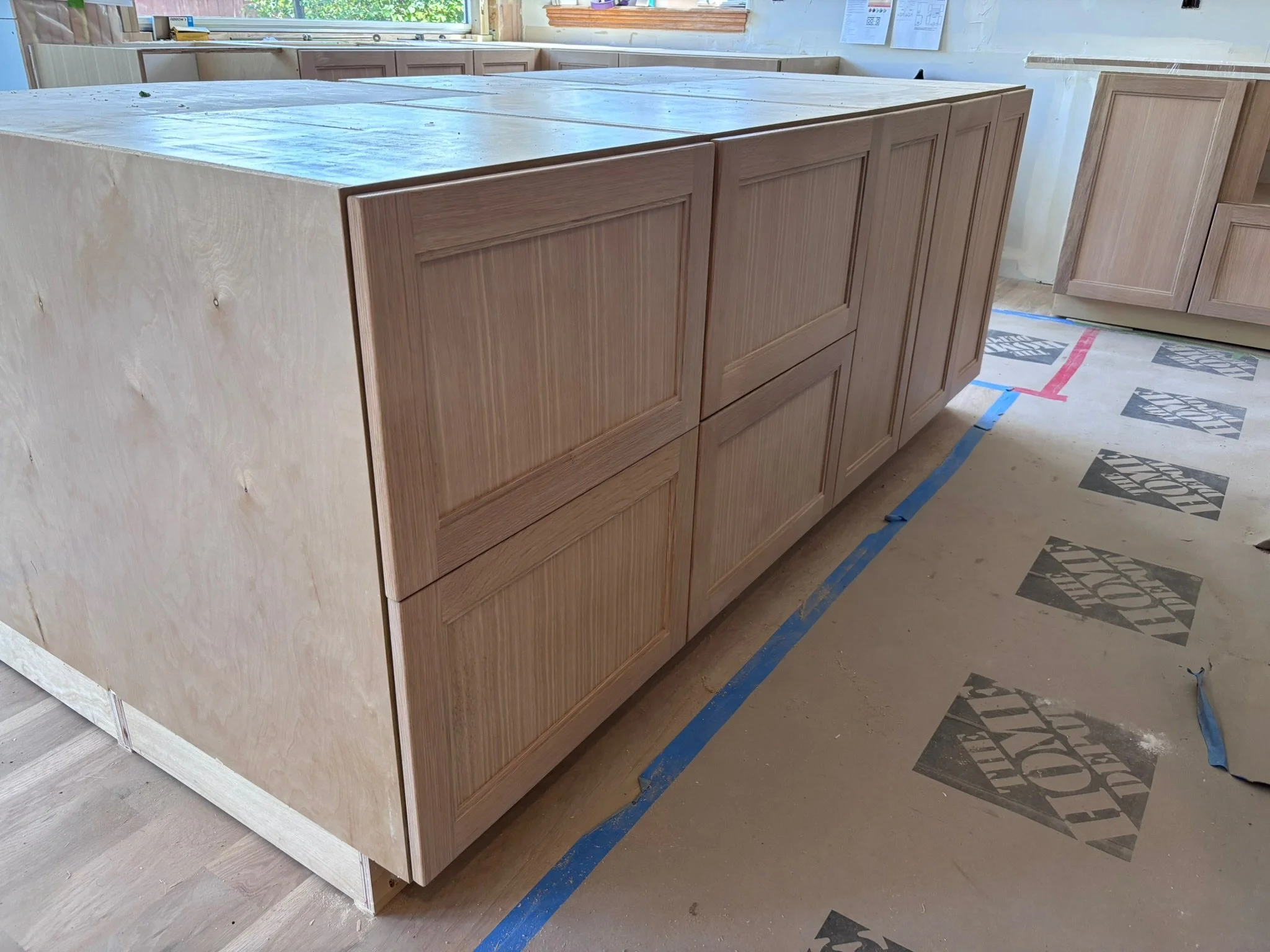 Unfinished kitchen island with wooden cabinetry and a light-colored tile top under construction