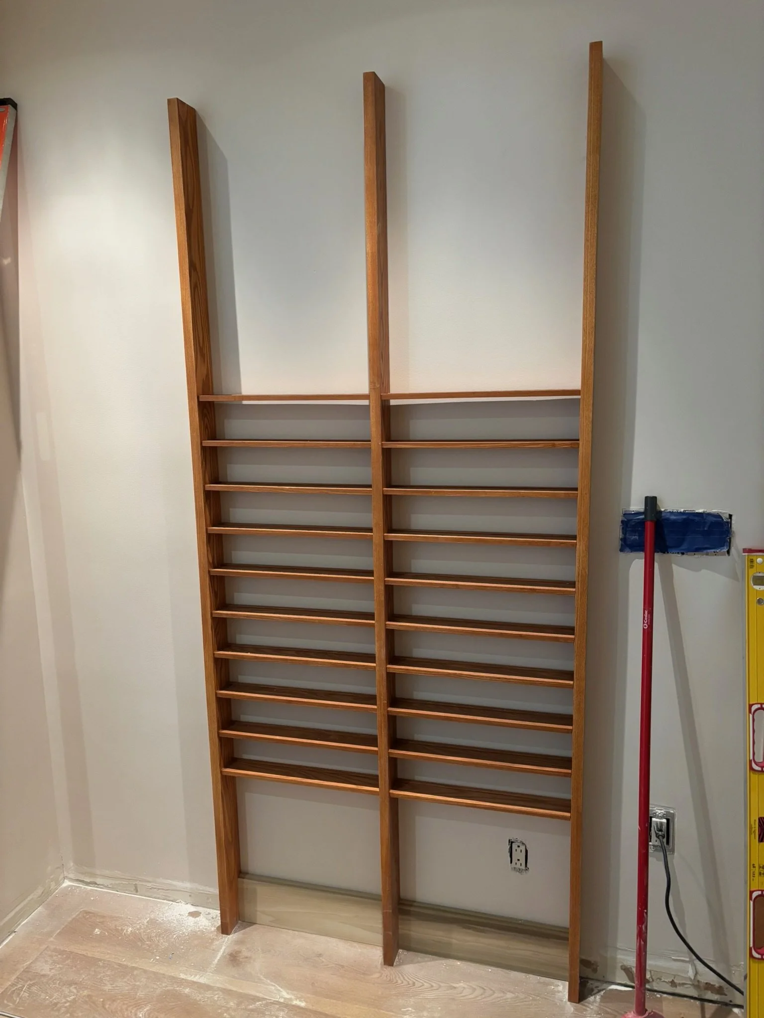 Wooden wall-mounted shelving unit in a room under construction.