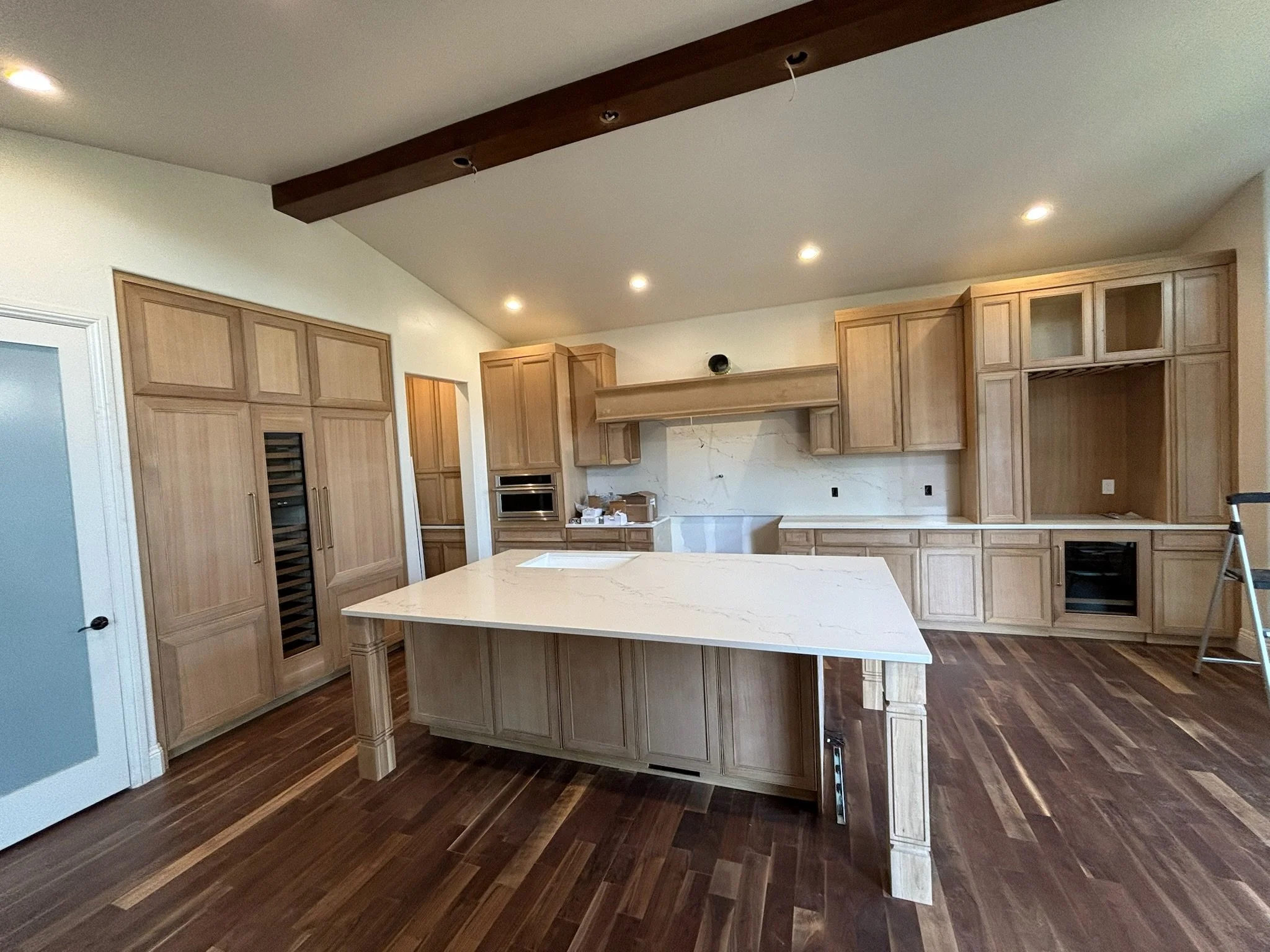 Kitchen with light wood cabinets and a large island with a white marble countertop, hardwood floors, and recessed lighting.