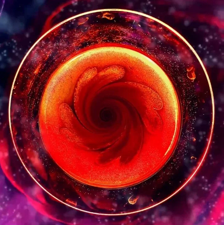 A swirling, abstract, cosmic scene with a bright, fiery red and orange vortex at the center, surrounded by a glowing outline and specks resembling stars in deep space.