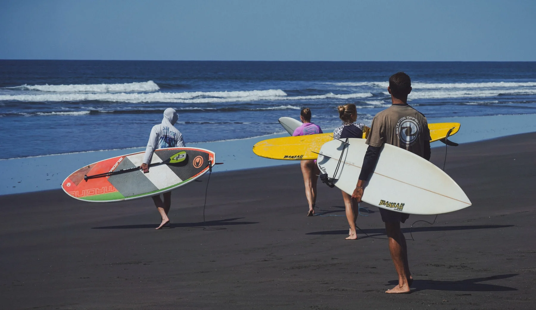 ISA-certified surf coach entering ocean with group lesson Costa Rica