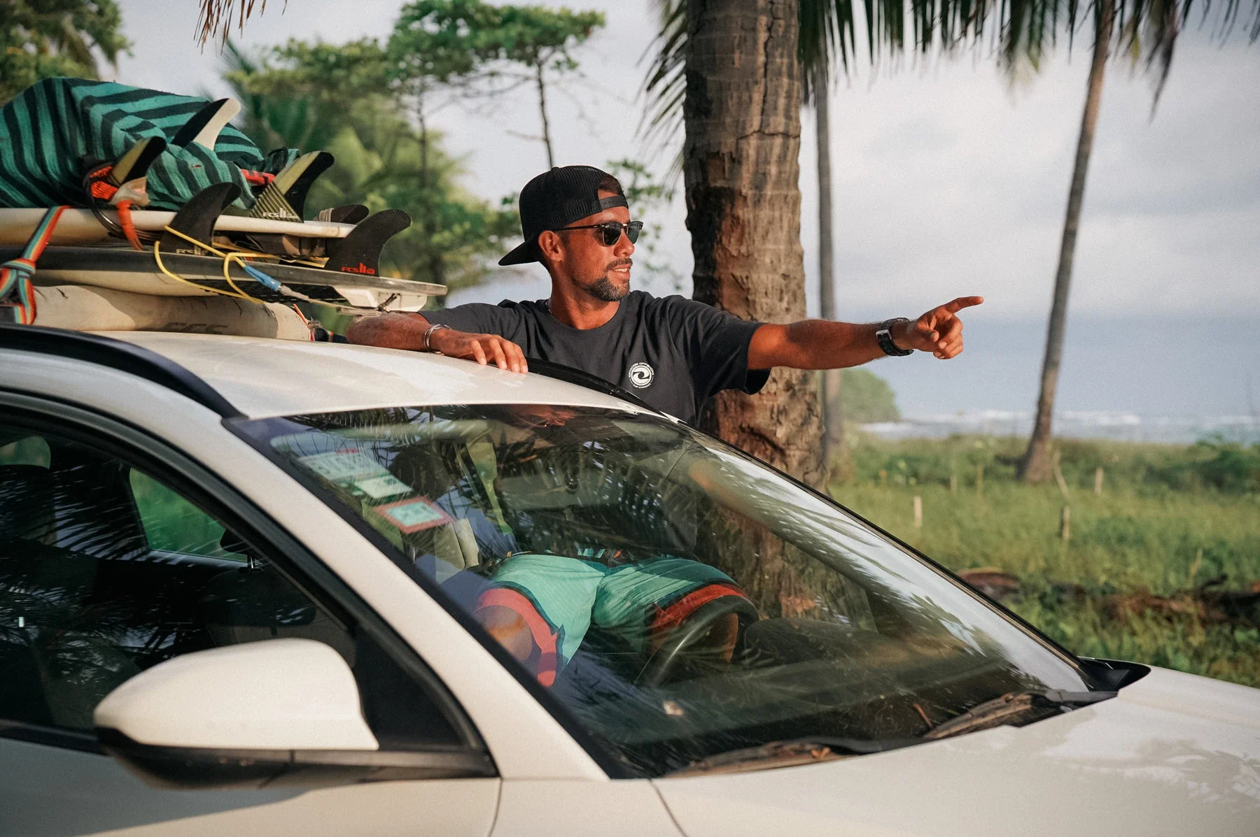 Surf guide sitting on the car explaining the surf spot to students during a guided surf trip in Costa Rica