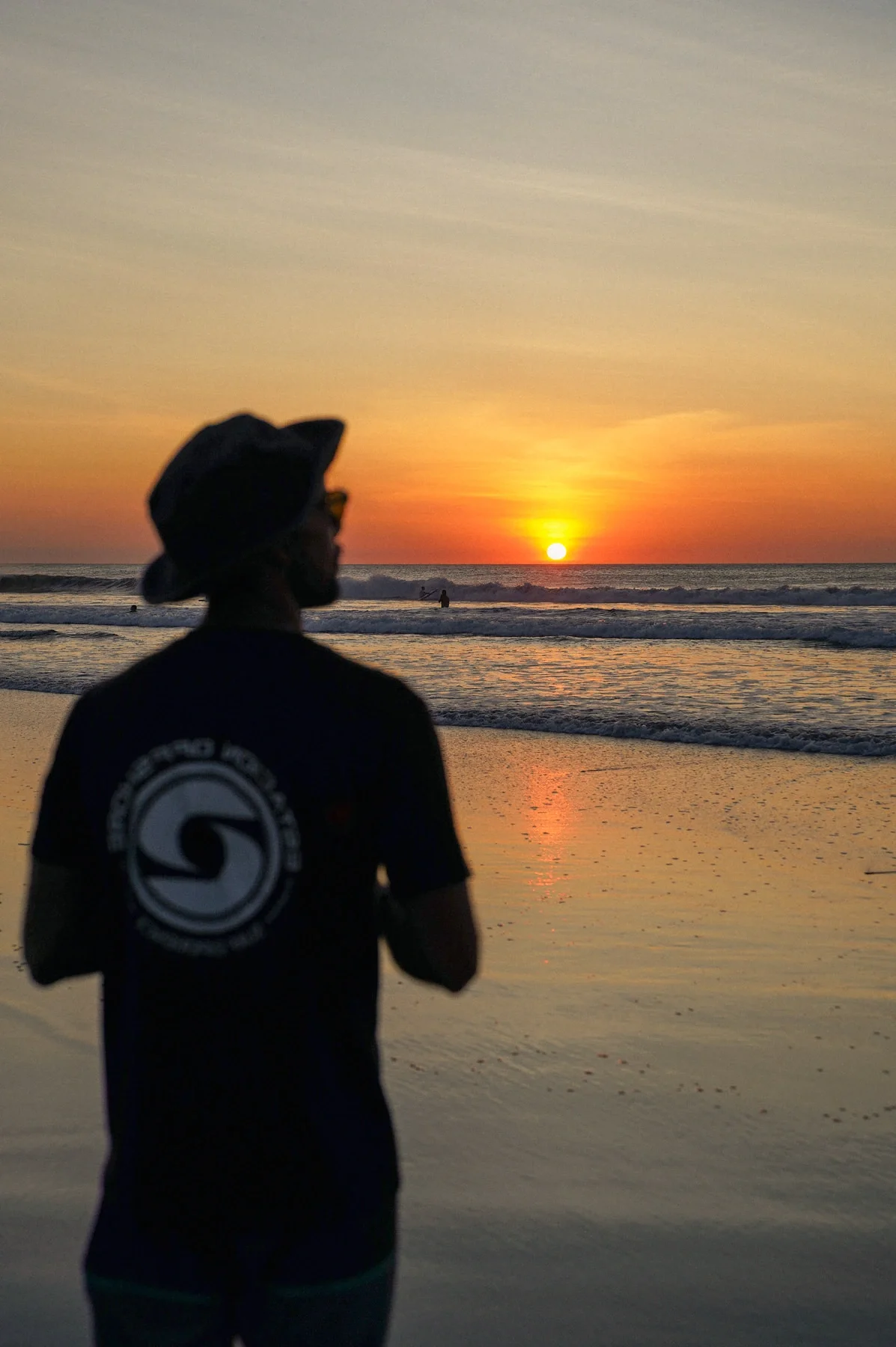 ISA-certified surf coach looking out at the ocean at sunset on the black sand beach of Marbella Costa Rica