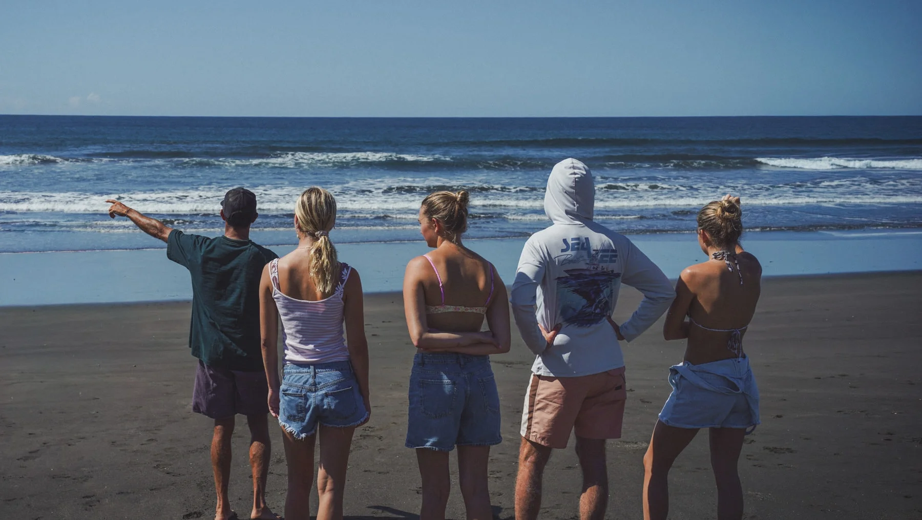 Surf guide briefing a family group on the beach during a surf trip in Costa Rica, pointing towards the waves before paddling out.