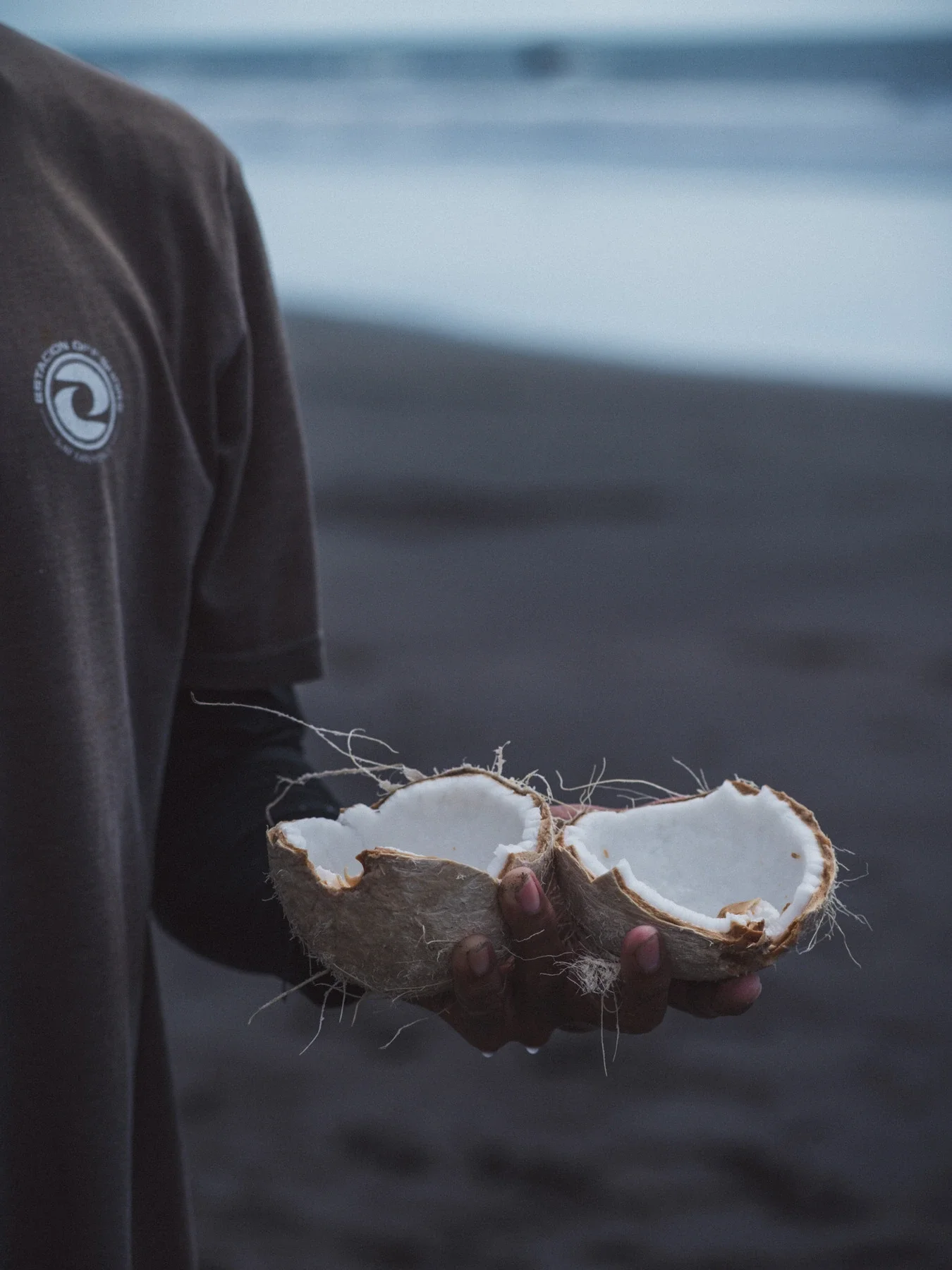 Surf instructor holding a cracked coconut after surf session in Costa Rica
