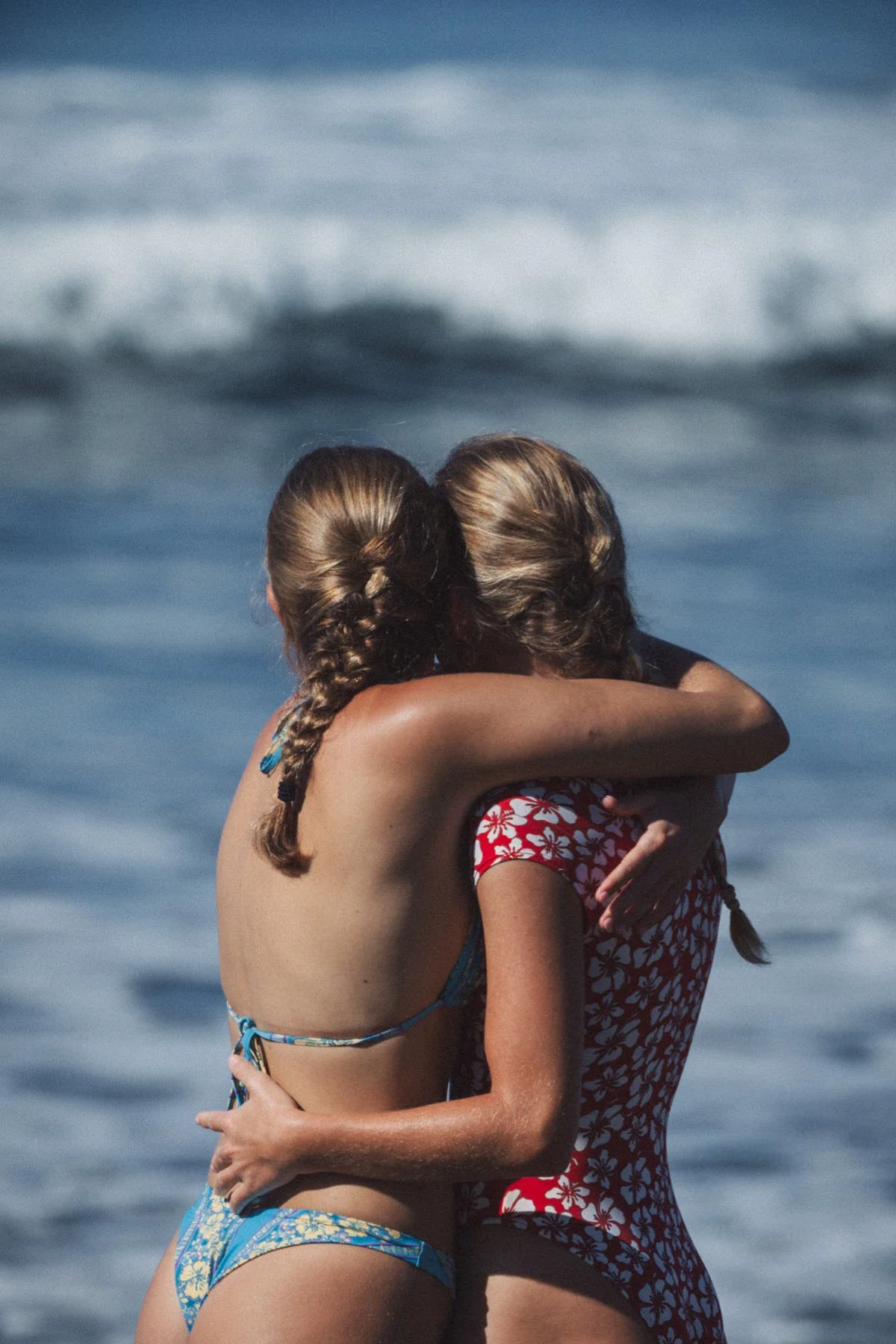 Two surfers celebrating on the beach during a surf trip in Costa Rica, ocean waves in the background.