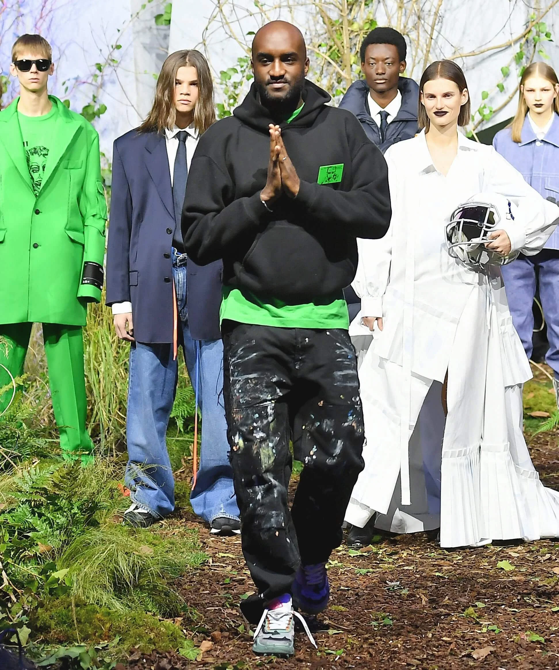 Group of fashion models and designer in stylish clothing on a forest runway.