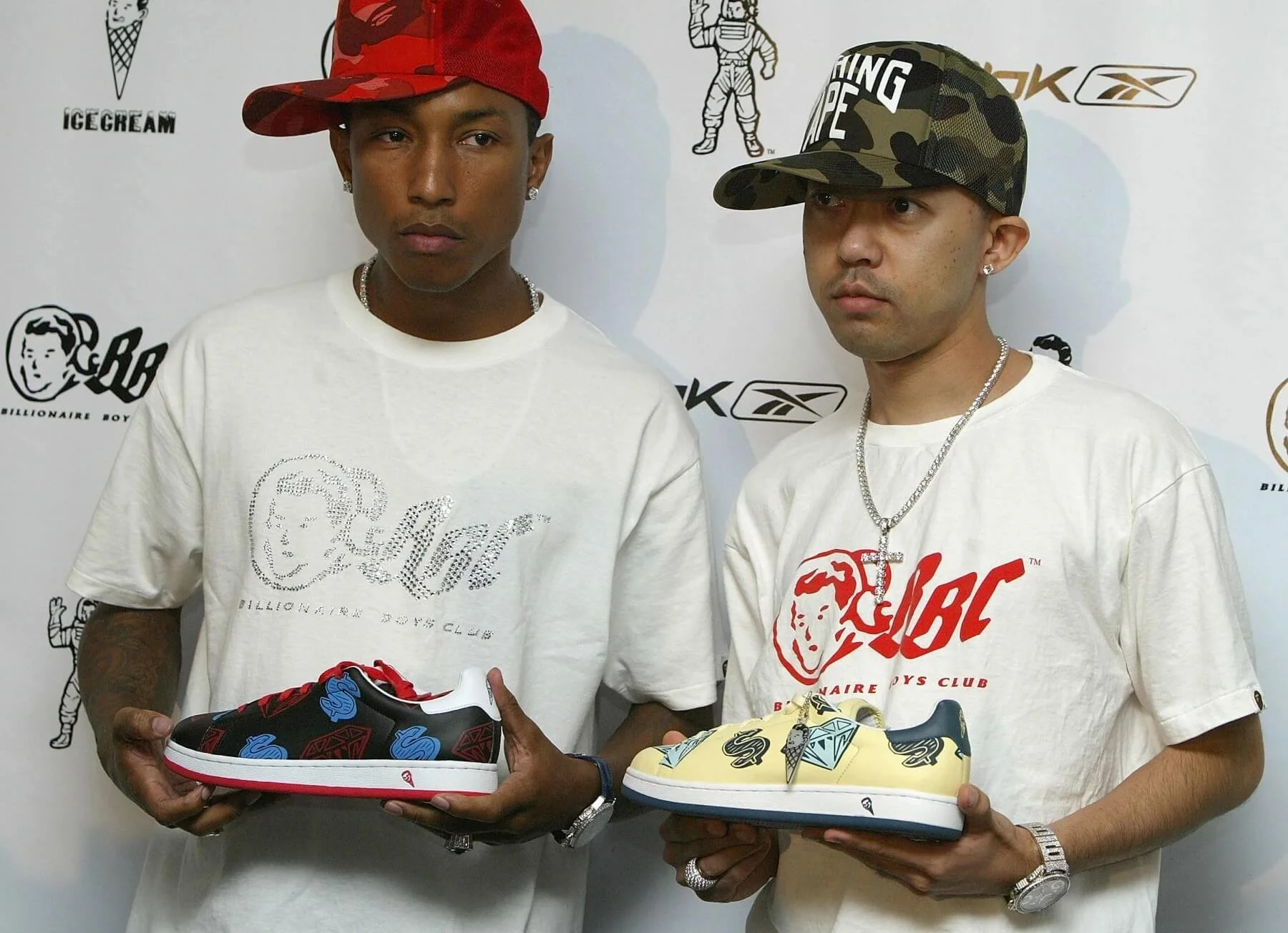 Two men wearing Billionaire Boys Club t-shirts and hats, holding colorful sneakers, standing in front of a branded backdrop featuring Ice Cream and Reebok logos.